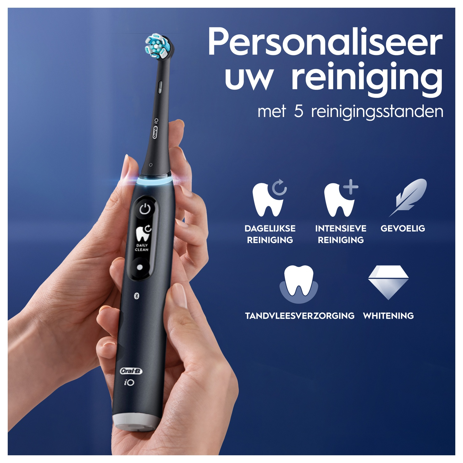 A person holding a black electric toothbrush with a blue and white brush head.