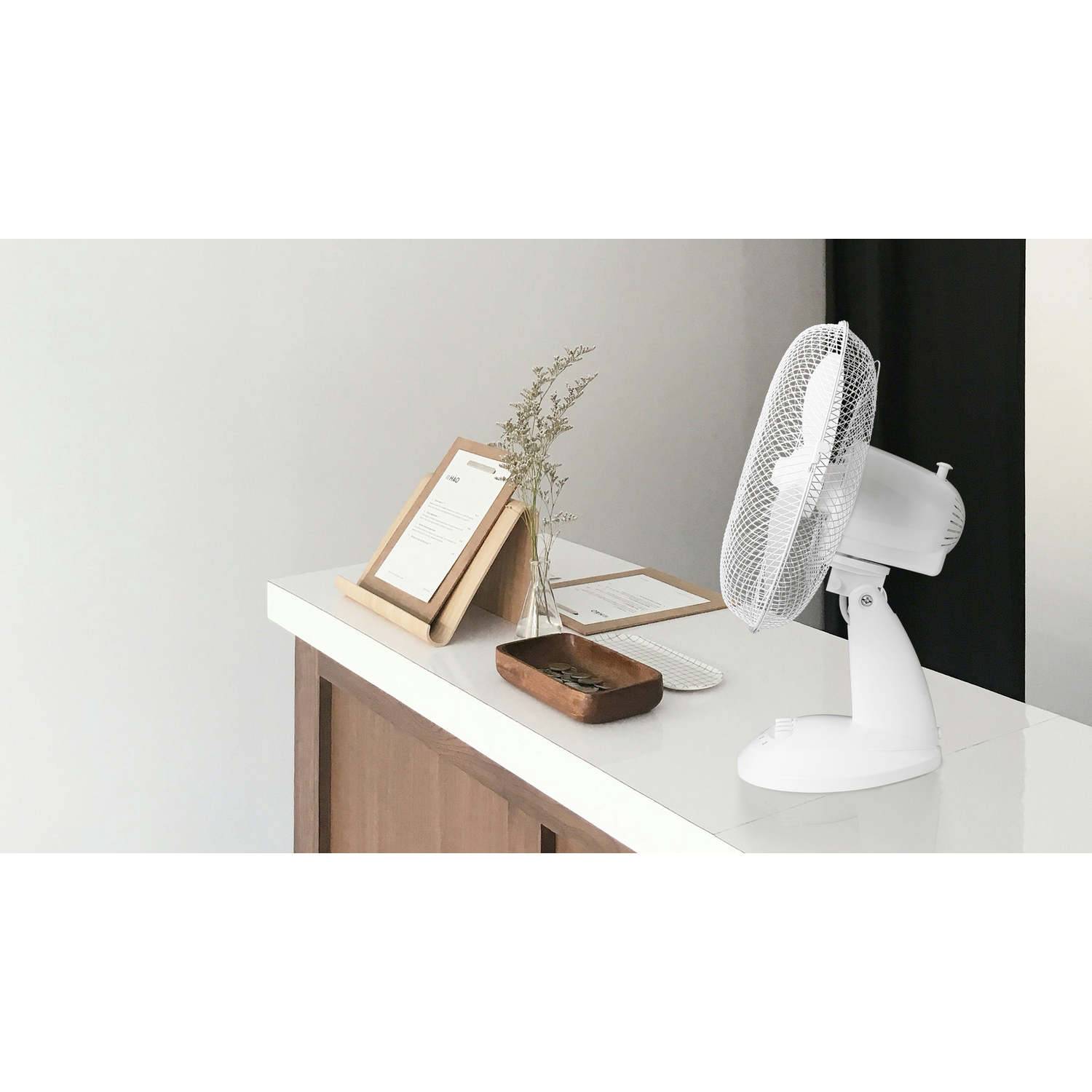 A white desk with a fan, documents, and a wooden tray.