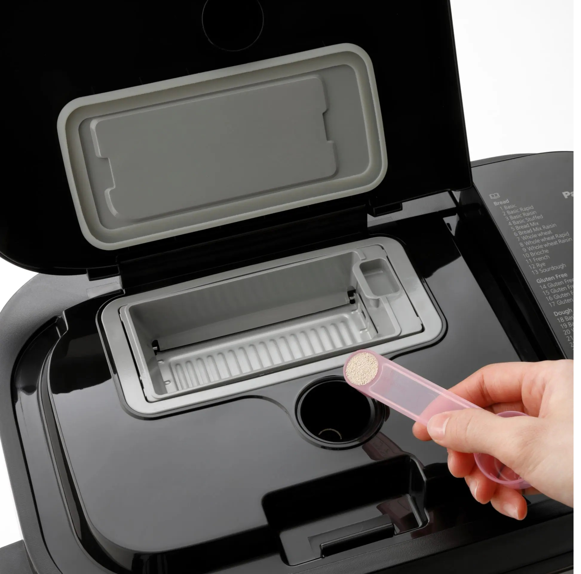 Maszyna do pieczenia chleba jest otwarta, pokazując komorę z różową łyżką.