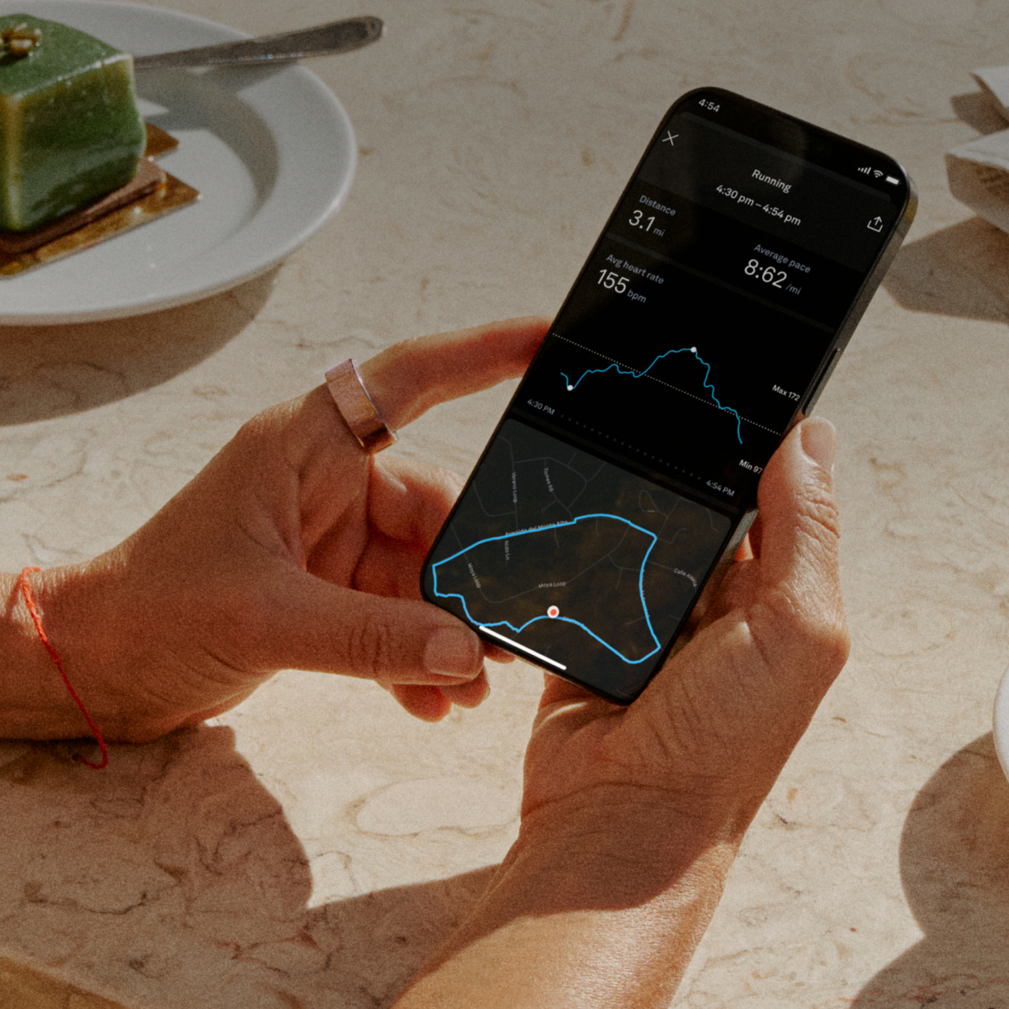 Hände, die ein Smartphone halten, das eine Lauf-App mit Statistiken und einer Karte zeigt.