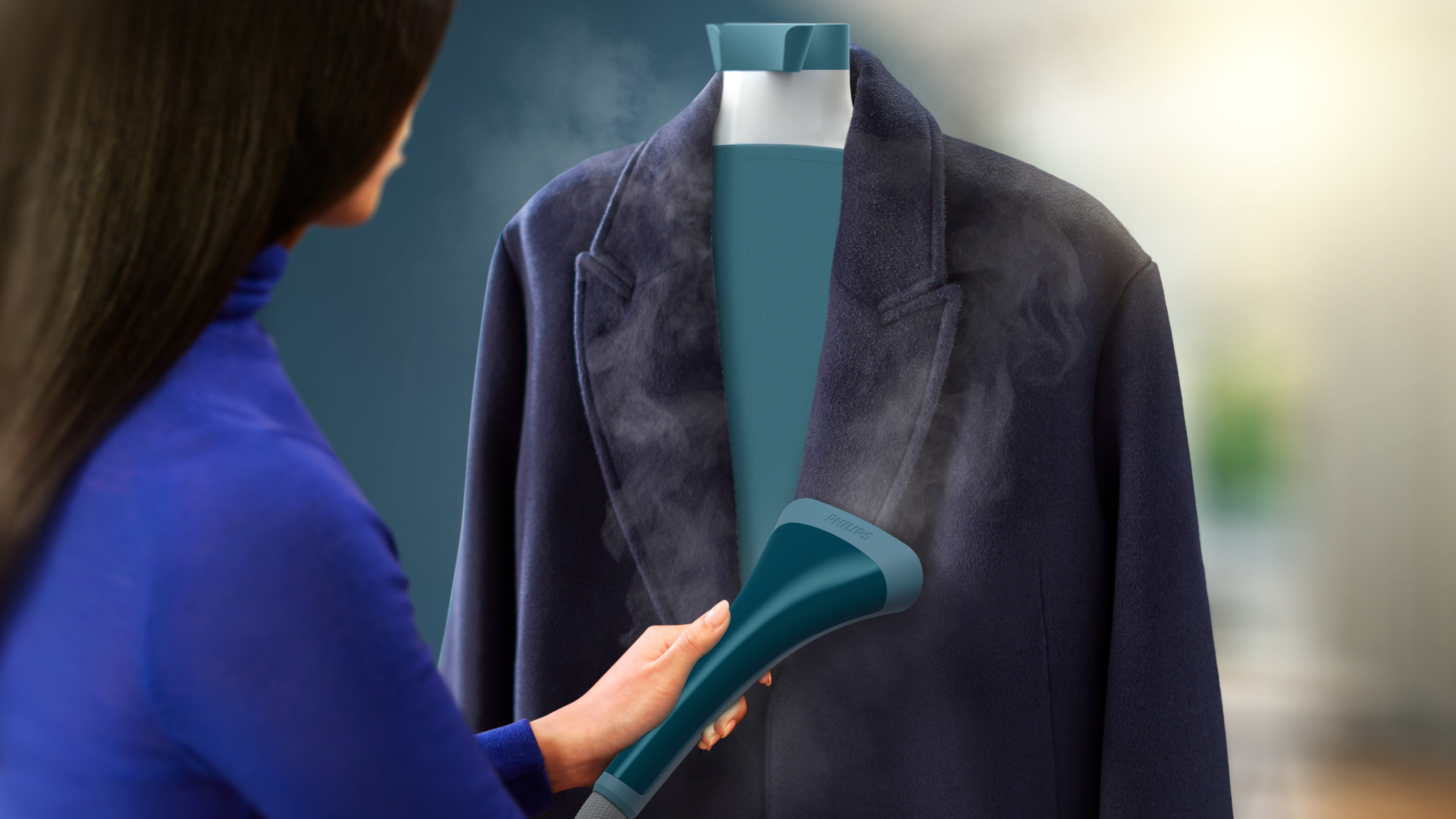 Una mujer planchando un abrigo azul marino con un vaporizador de ropa portátil.