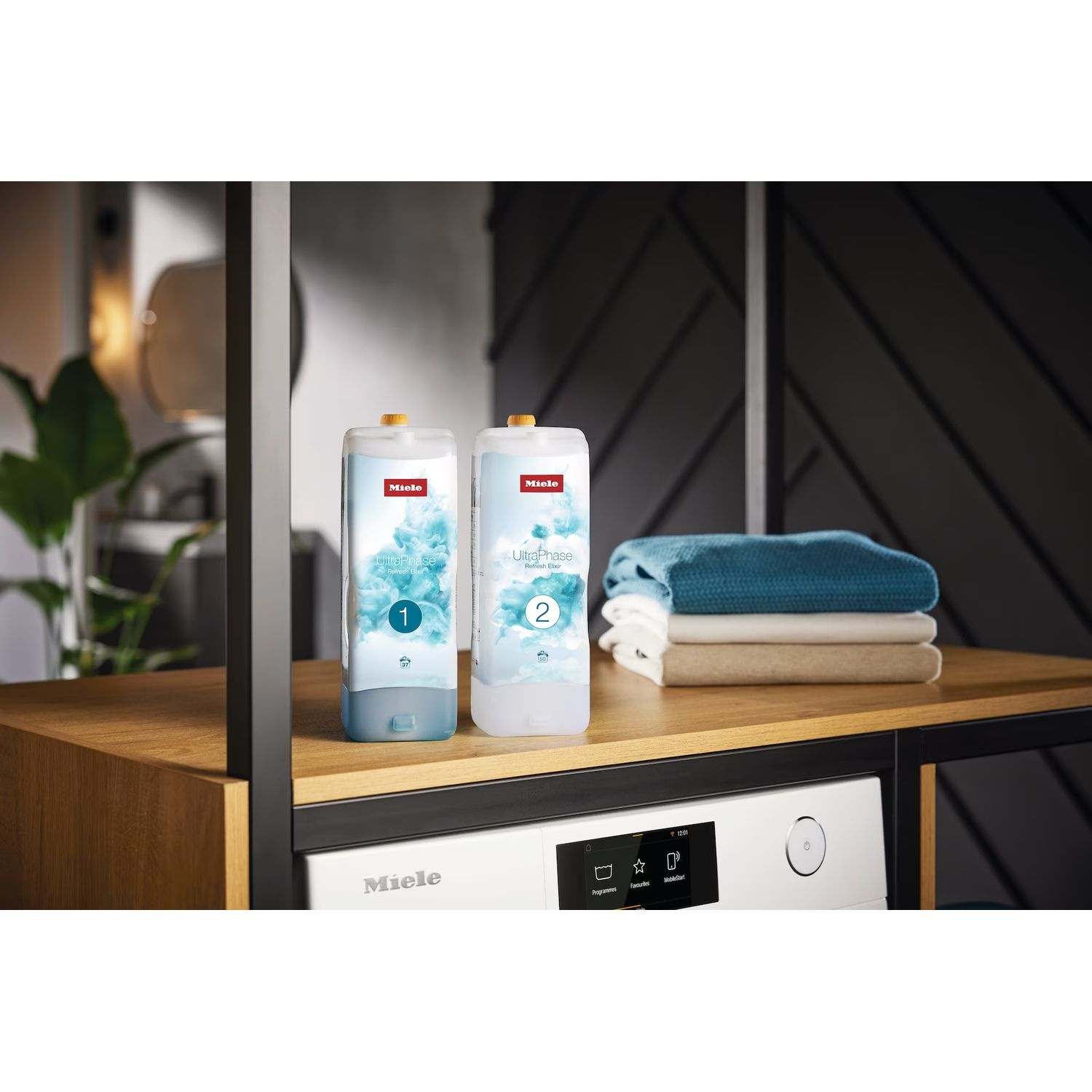 Two laundry detergent bottles and folded clothes on a washing machine.