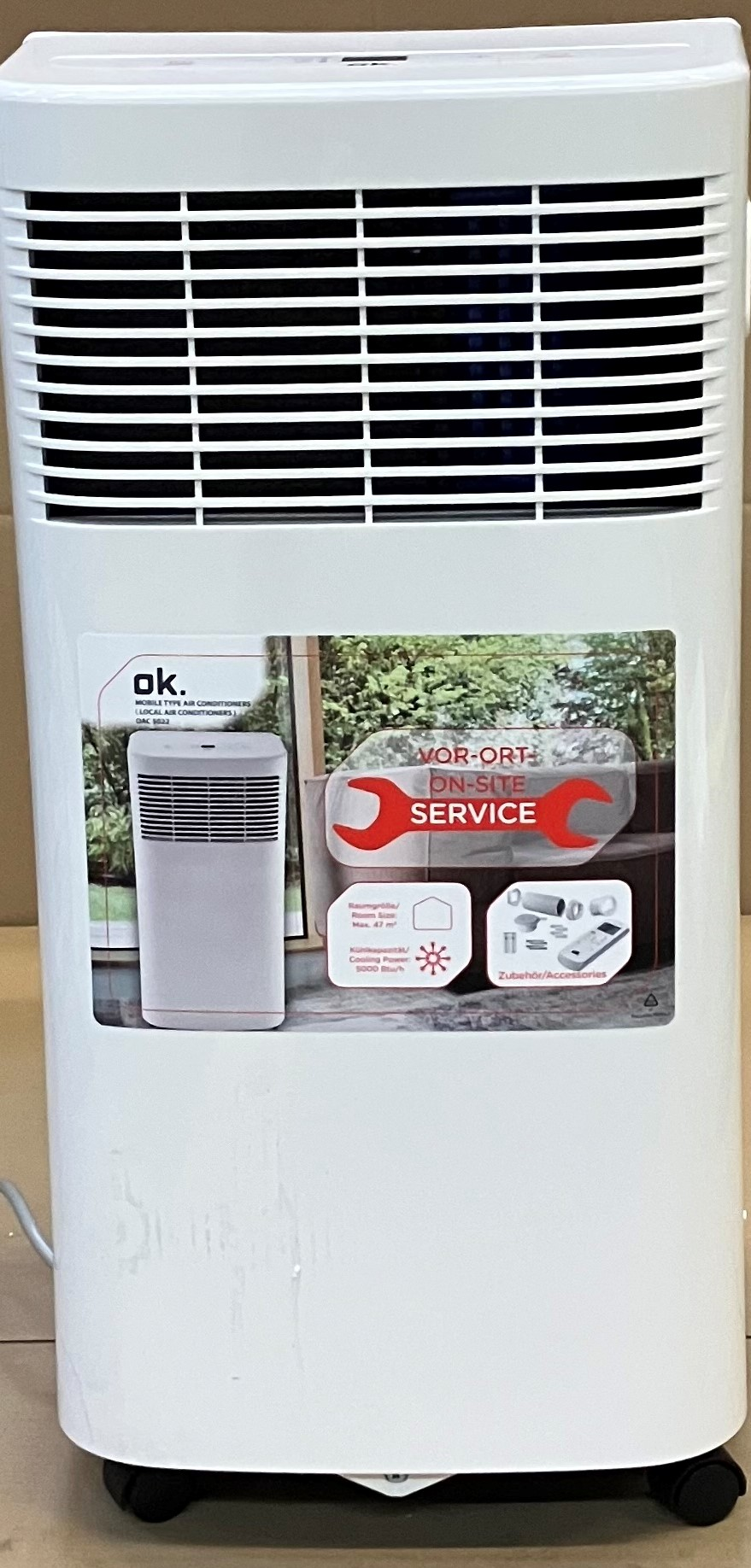 Biała przenośna klimatyzacja z naklejką serwisową.