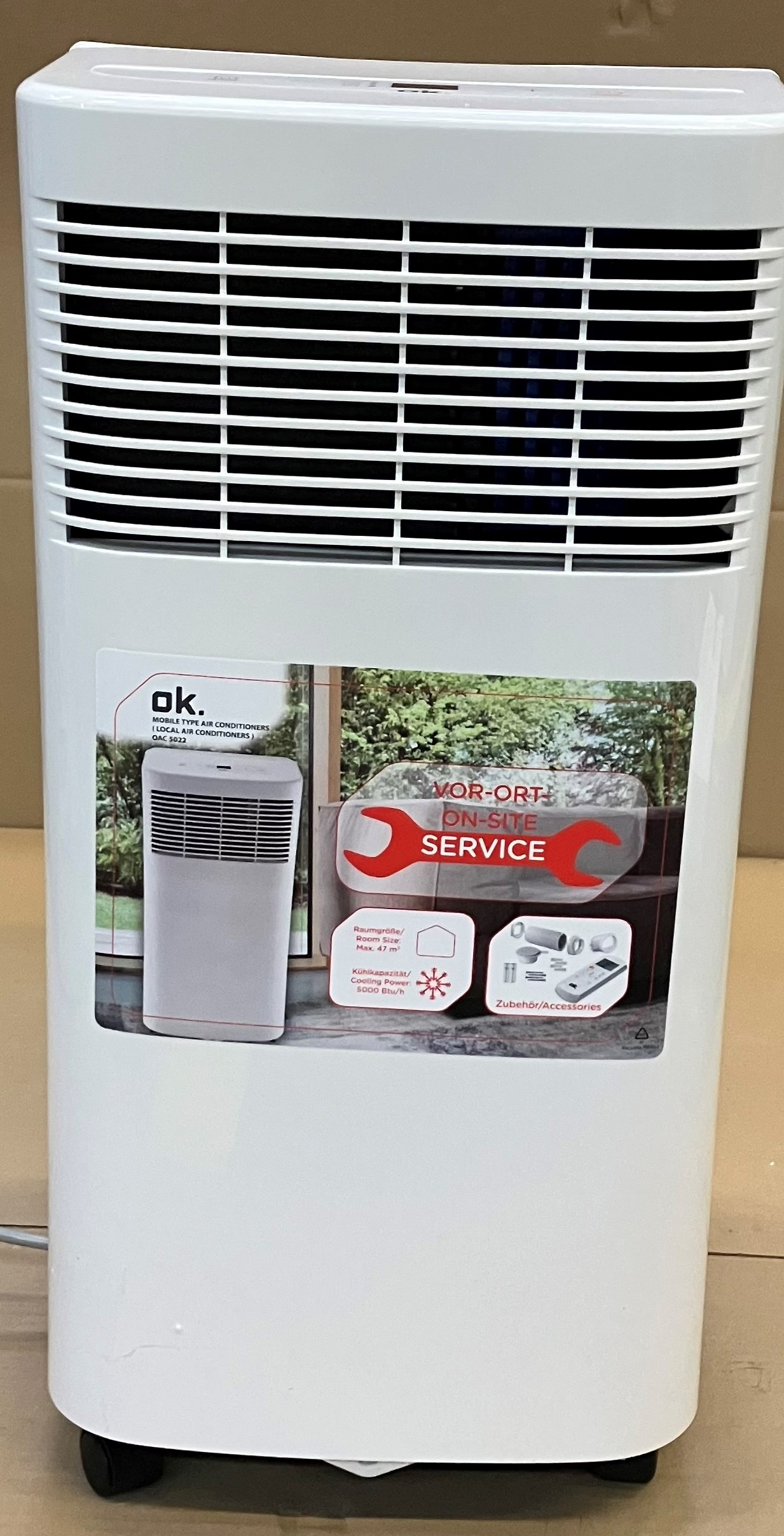 Biała przenośna klimatyzacja z naklejką serwisową.