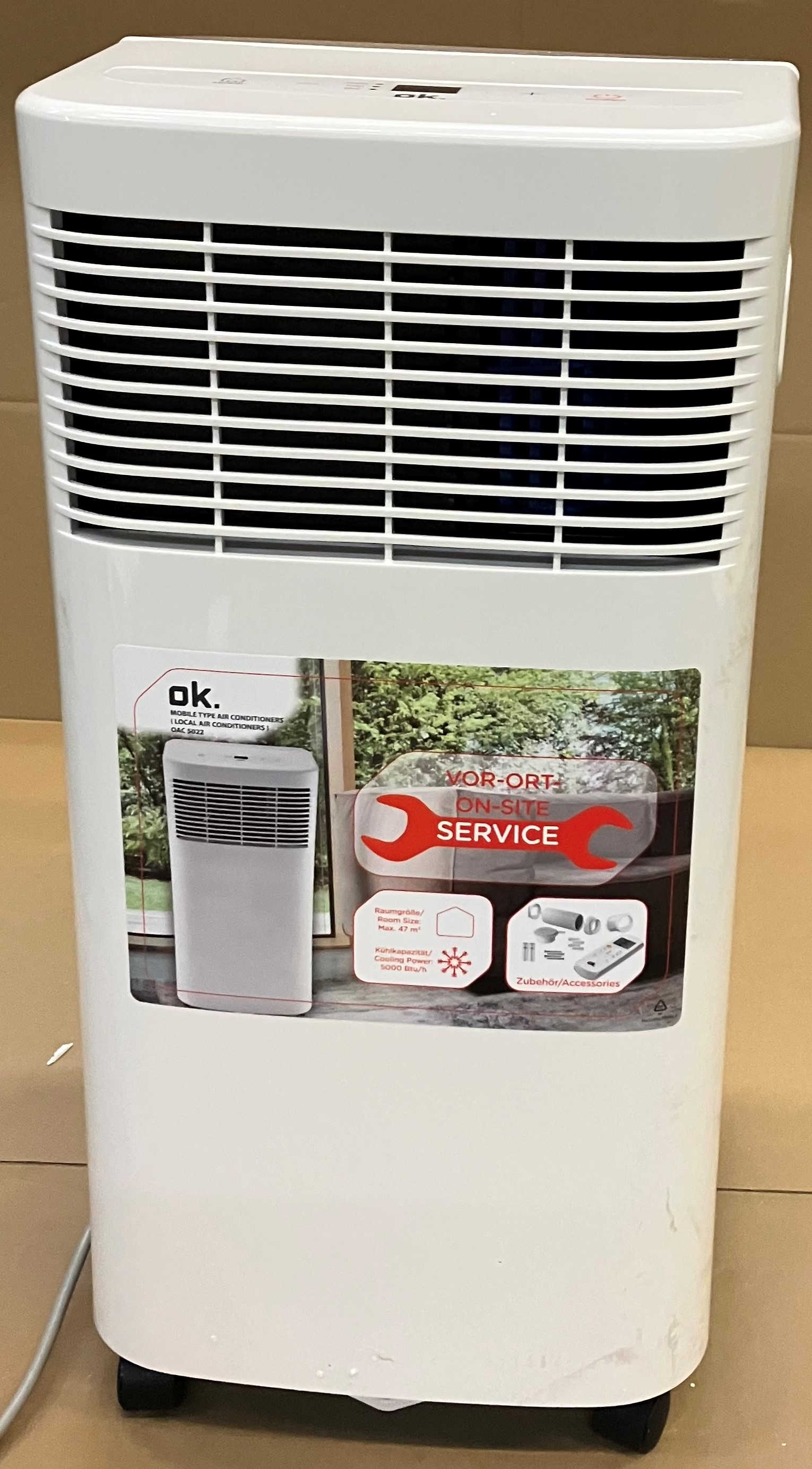 Biały klimatyzator OK z naklejką na oknie pokazującą scenę na zewnątrz.