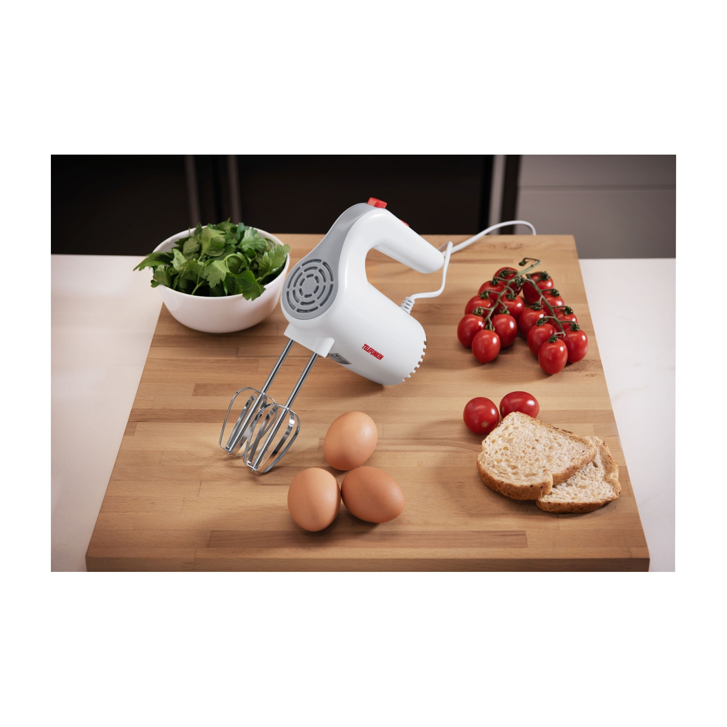 Frullatore a mano bianco con uova, pomodori e pane su un tagliere.