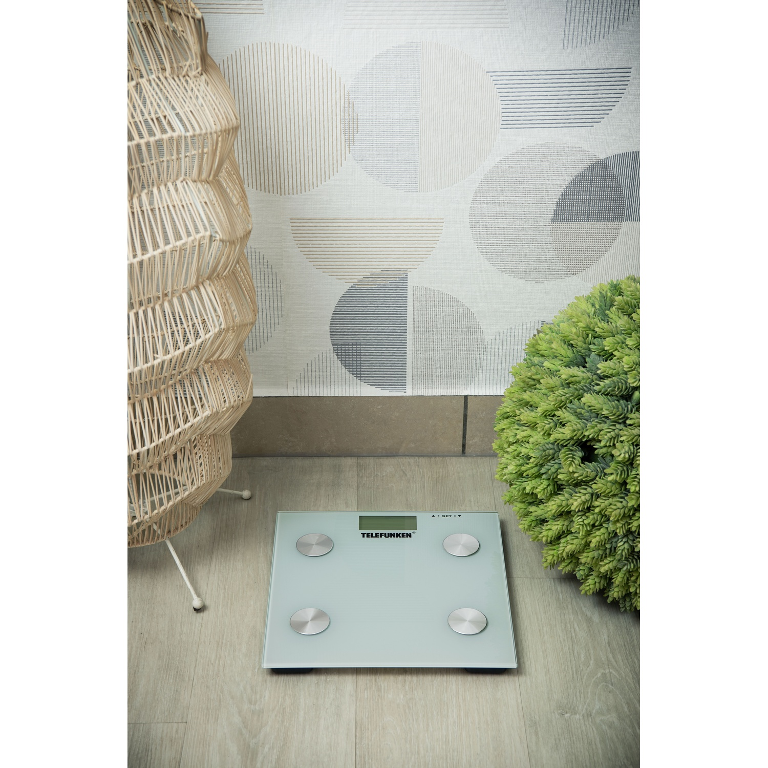 Bilancia da bagno con base verde e pianta decorativa e supporto in vimini.