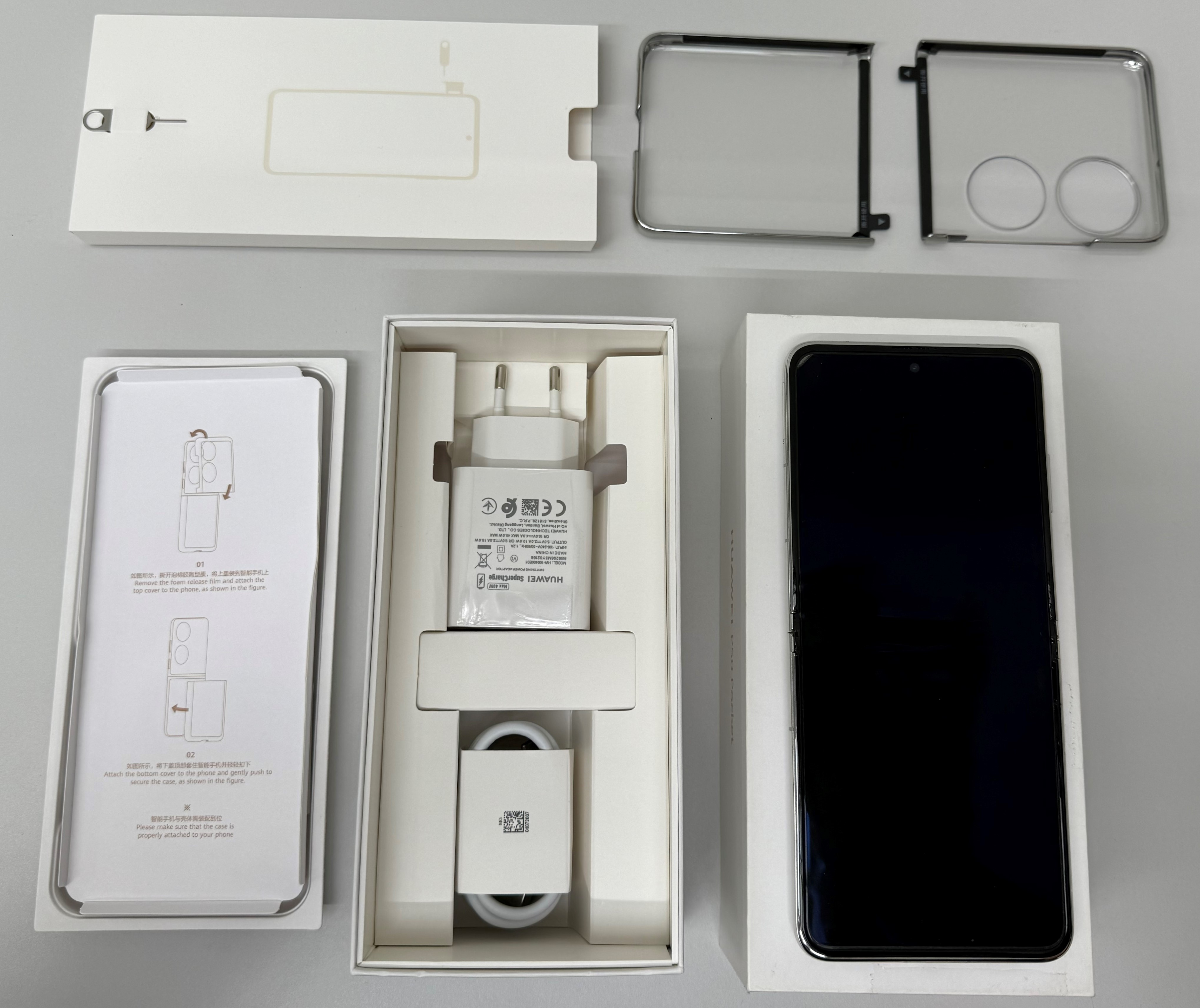 Smartfon i akcesoria w otwartym pudełku na białej powierzchni.