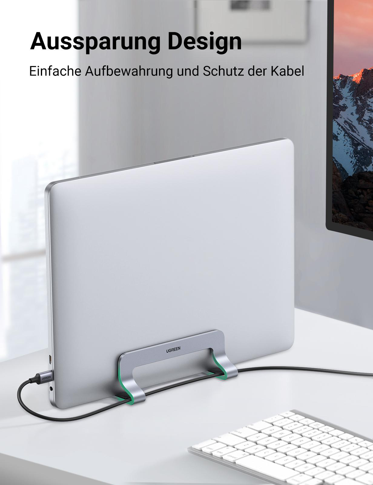 Silberner Laptop in einem Ständer mit schwarzem Kabel. Weiße Tastatur sichtbar.