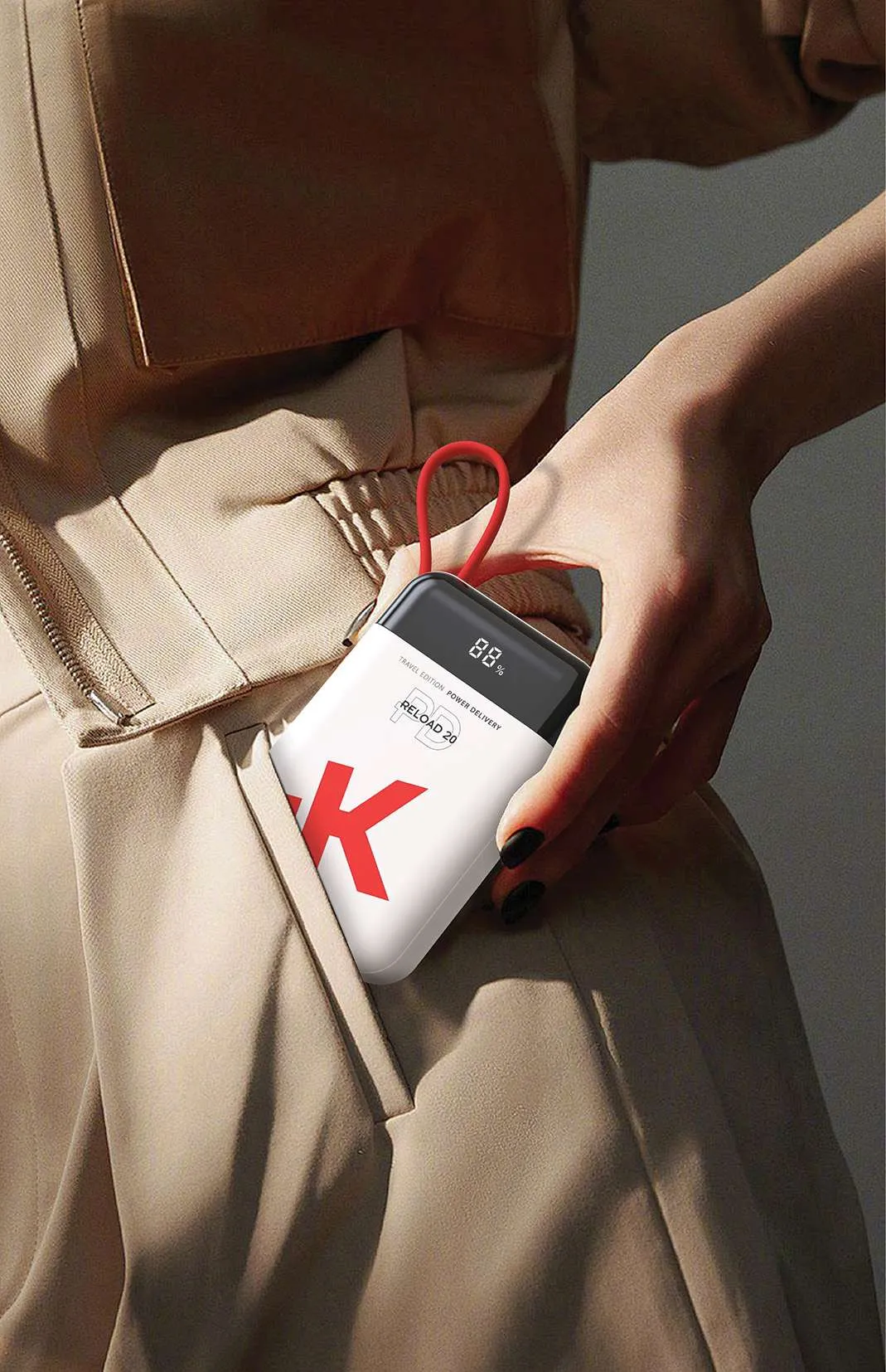 Egy fehér-piros power bank a zsebben. Egy kéz tartja.