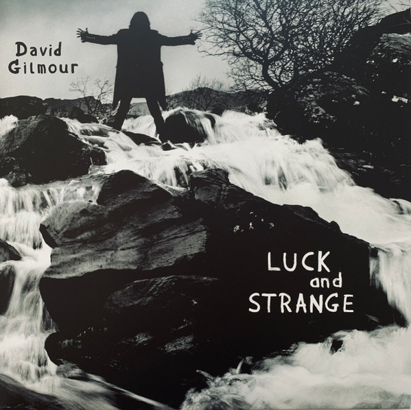 Albumhoes: David Gilmour staat op rotsen bij een waterval met uitgestrekte armen.