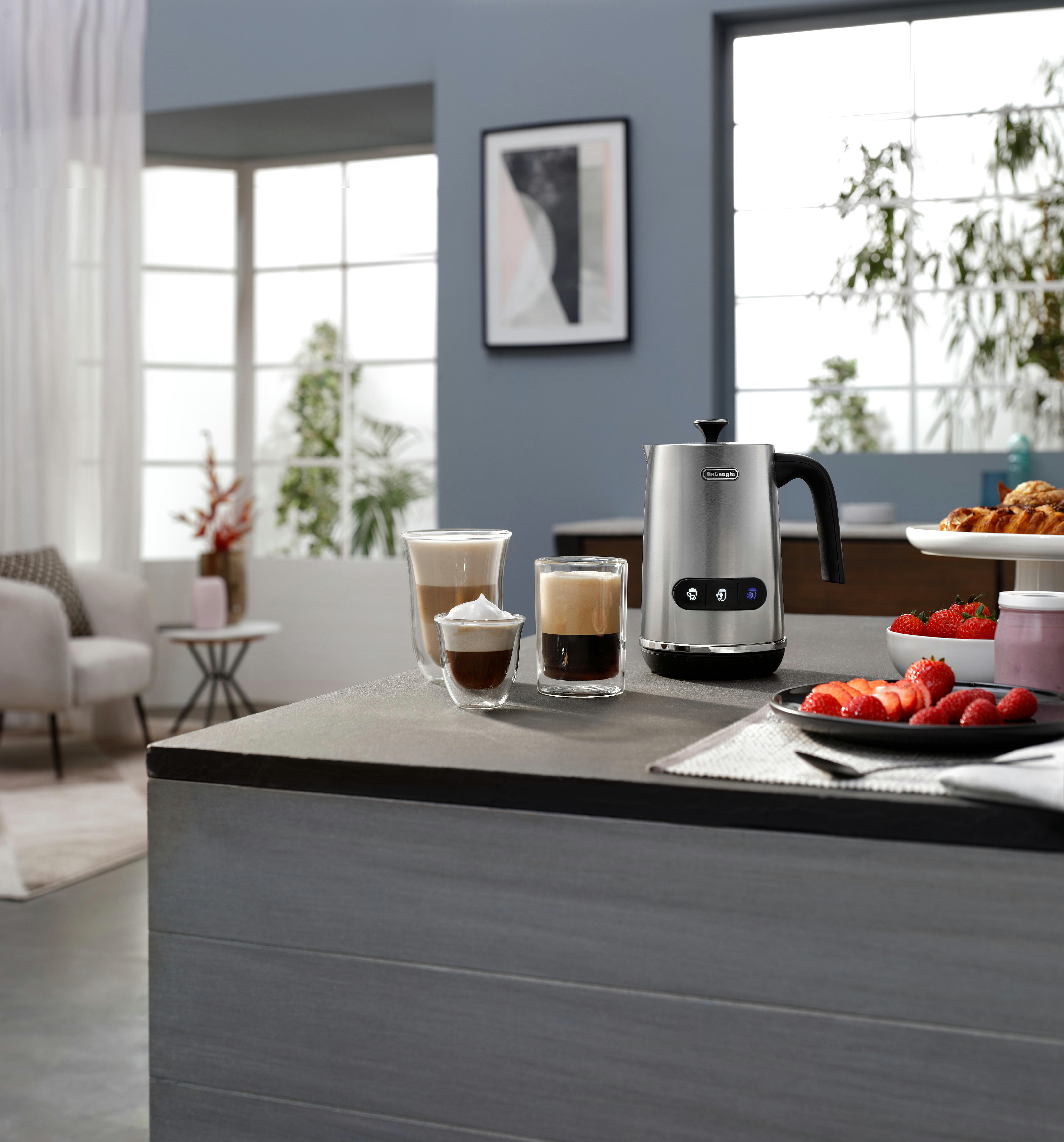 Küchenszene mit Kaffee, Milchaufschäumer und Erdbeeren auf einer Arbeitsplatte.