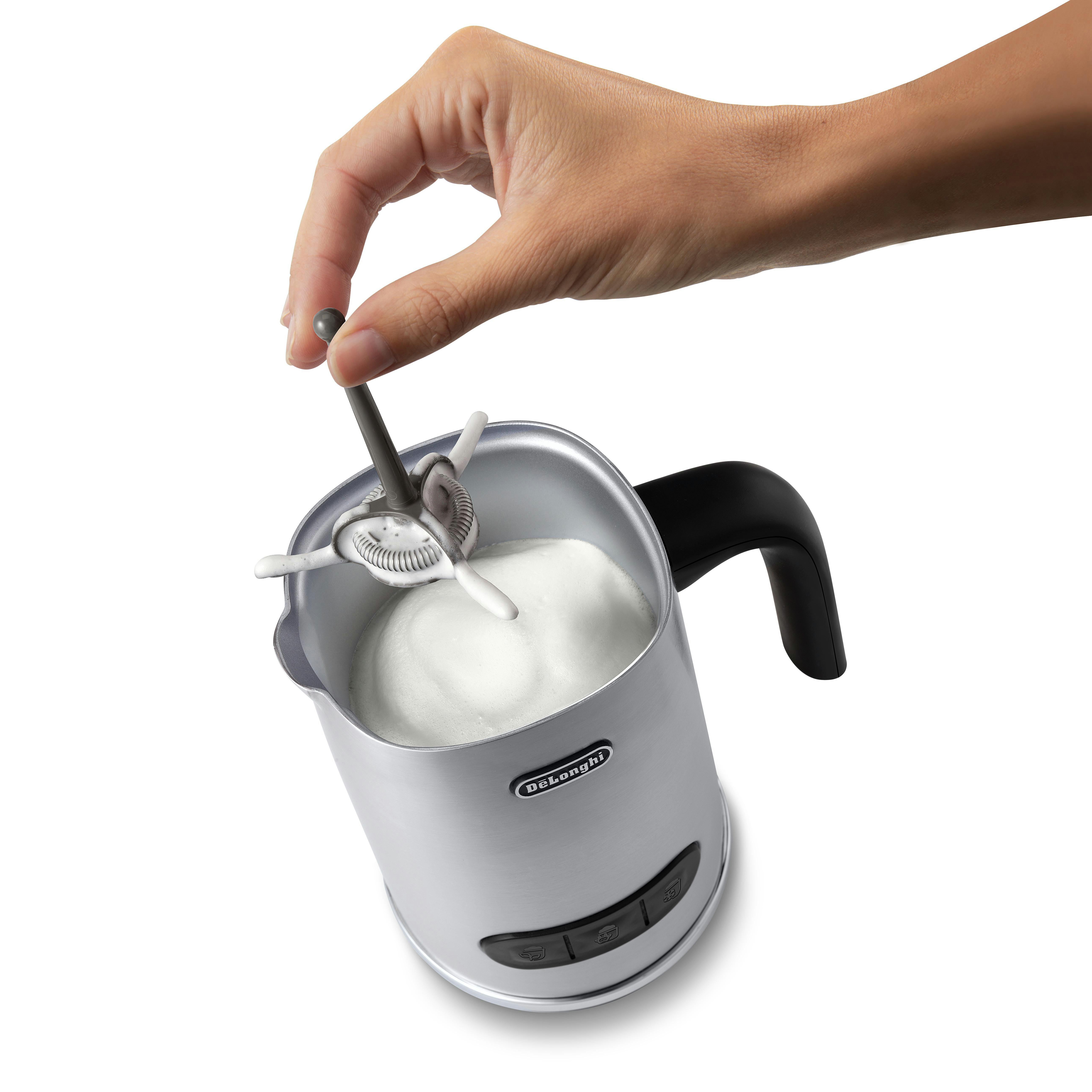 Hand hält Schneebesen in silbernem Milchaufschäumer mit weißem Schaum.
