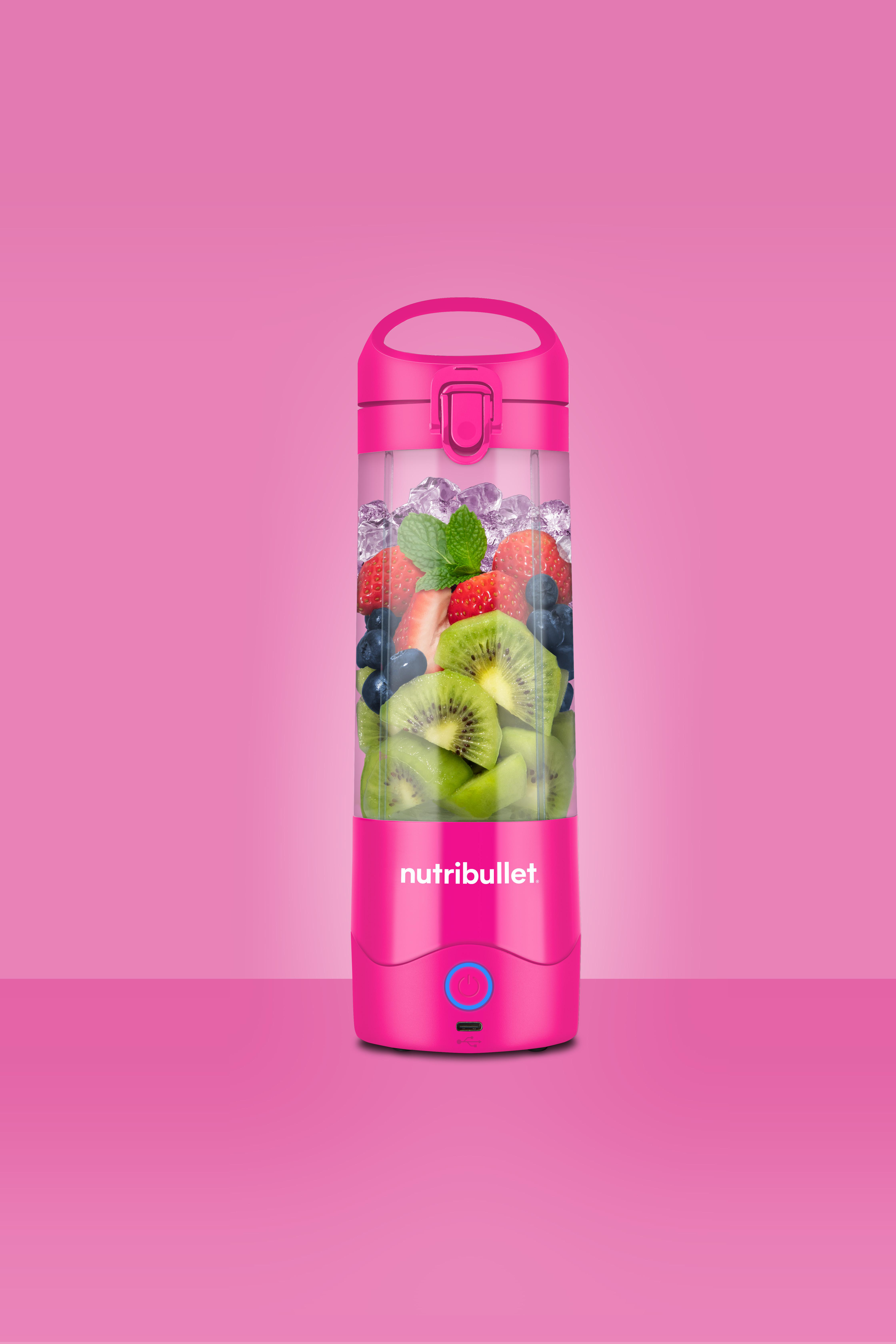Rosa Nutribullet-Mixer mit Früchten und Eis, auf rosa Hintergrund.