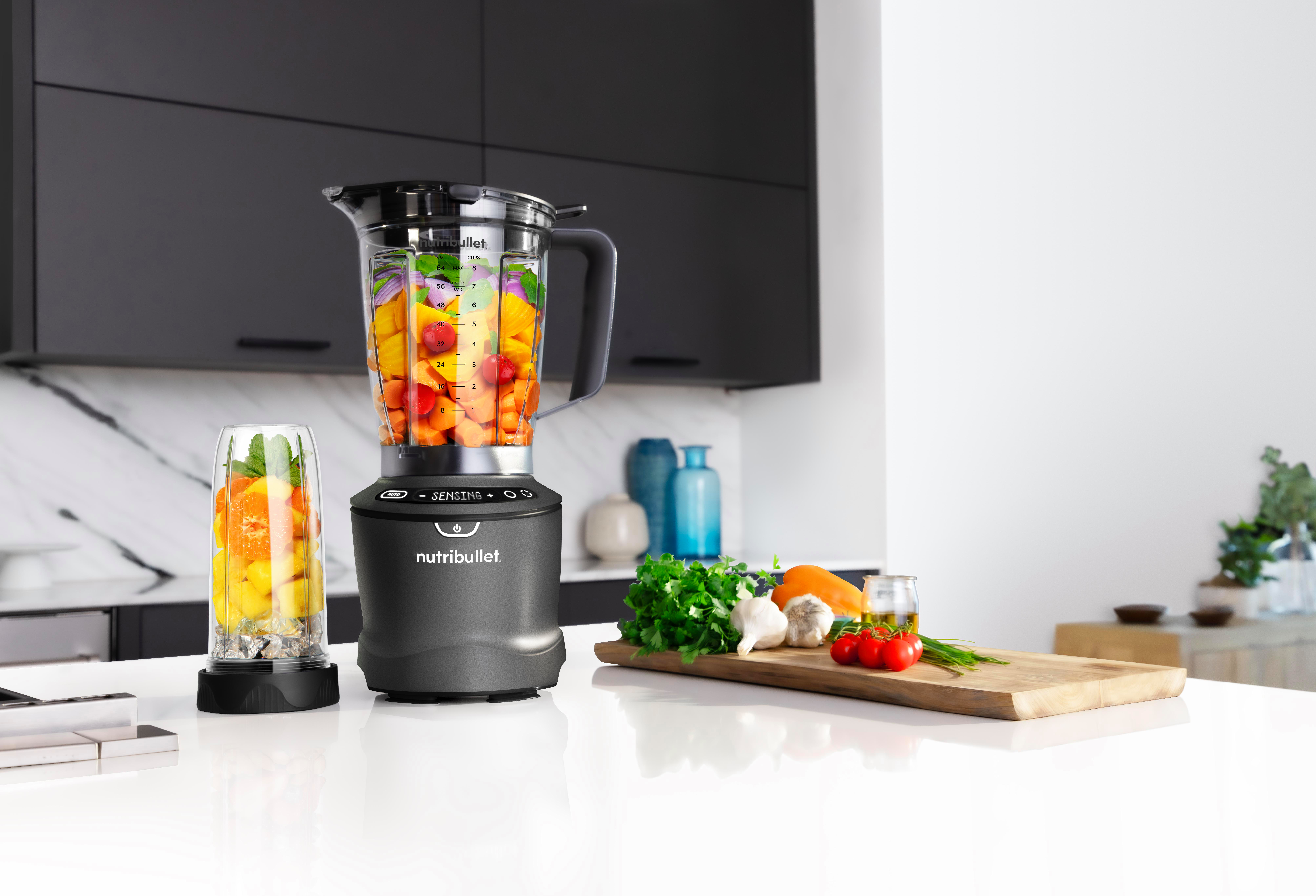Ein Mixer mit Früchten im Inneren und ein kleinerer Mixer sowie Zutaten daneben.