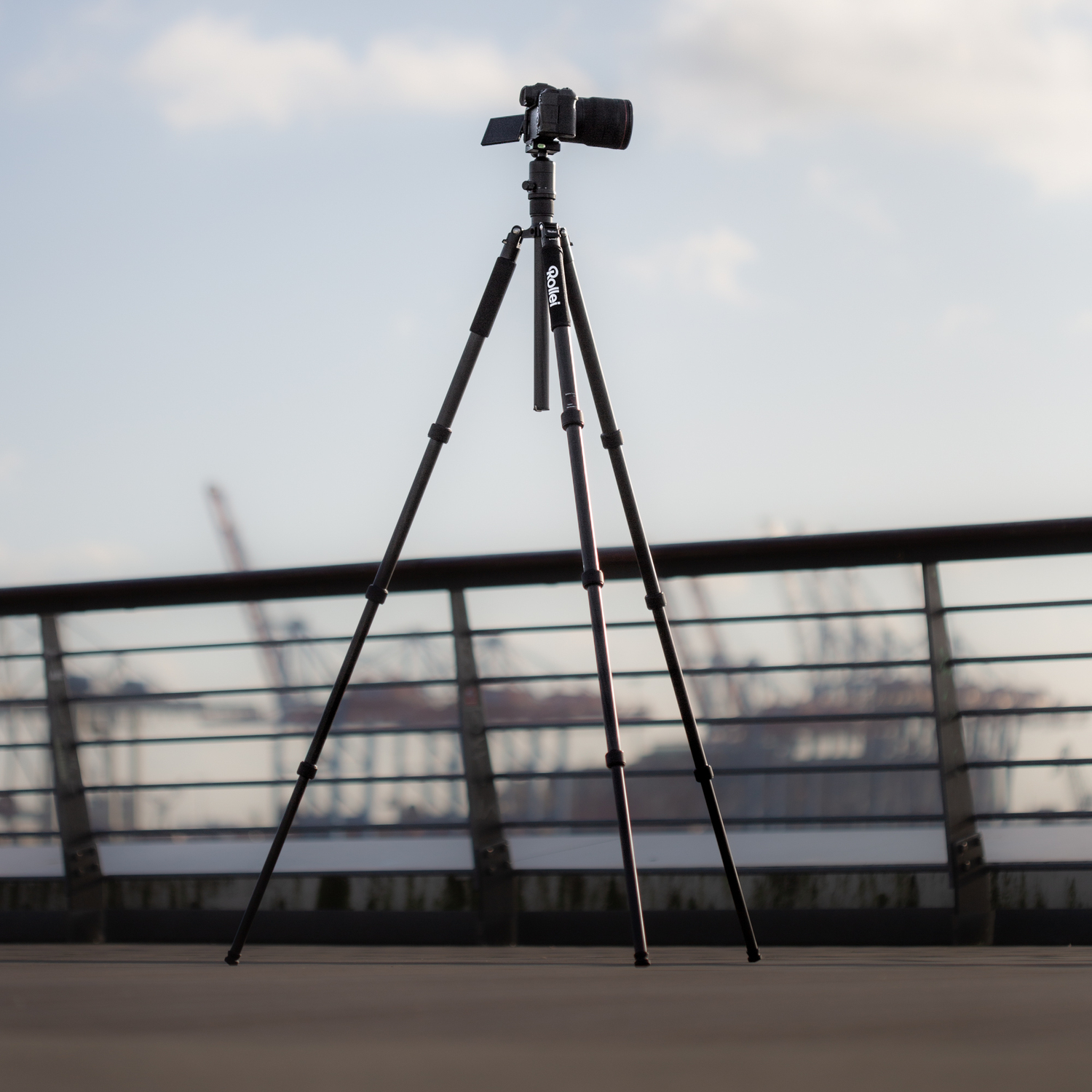 A tripod with a camera on top, on a wooden surface.