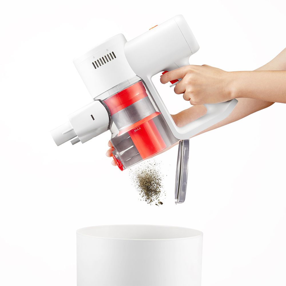Une personne vide un aspirateur blanc et rouge.