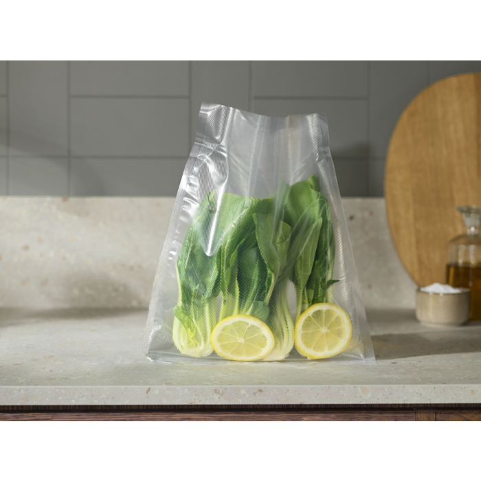 Zöld bok choy és citromszeletek egy átlátszó műanyag zacskóban a pulton. A háttér egy konyha.