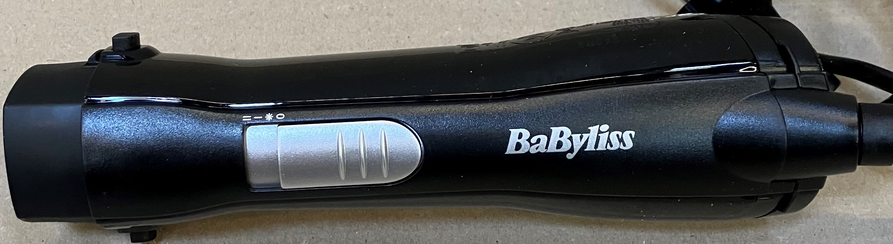 Czarna prostownica Babyliss ze srebrnym suwakiem i symbolami.