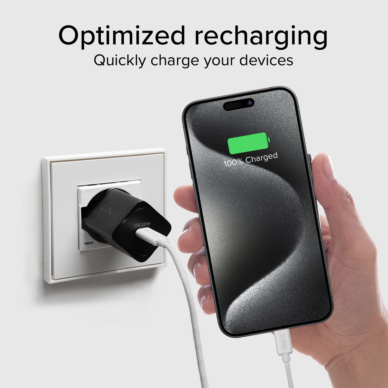 Téléphone en charge avec câble et chargeur branchés au mur, affichant 100% chargé.