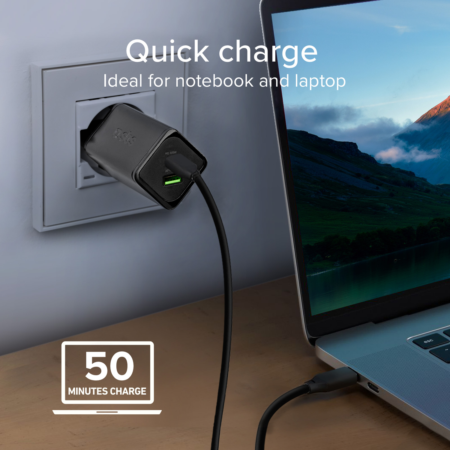 Black charger plugged into a white wall socket, charging a laptop.