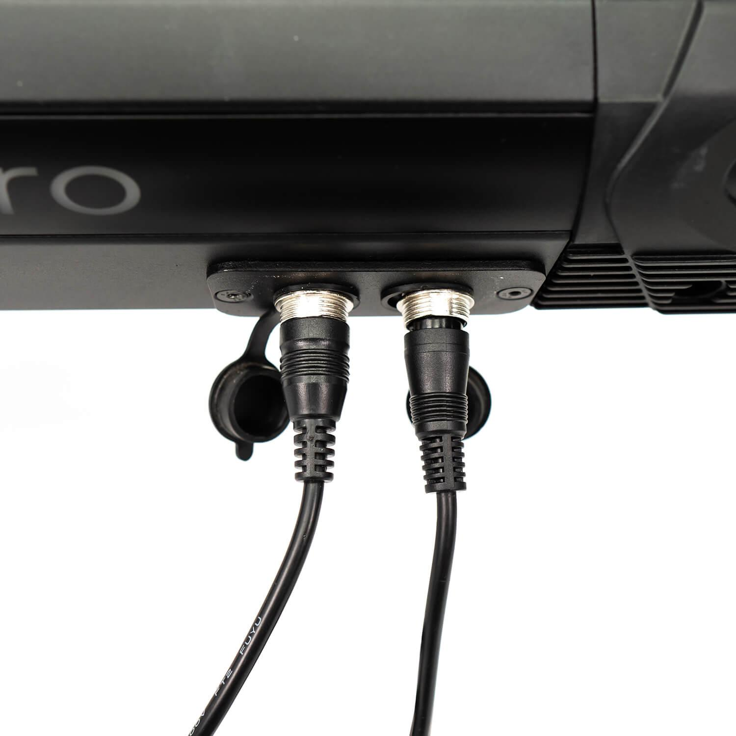 Dos cables negros con conectores plateados enchufados a un dispositivo negro.
