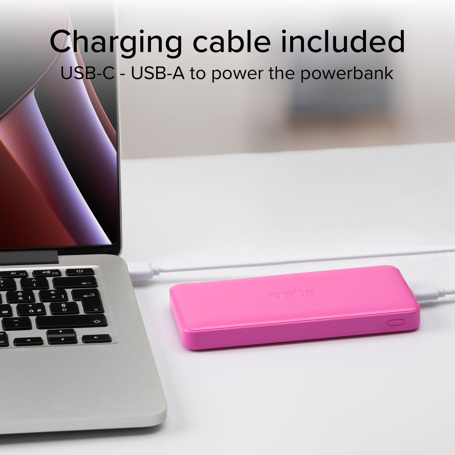 A pink power bank is connected to a laptop with a white charging cable.