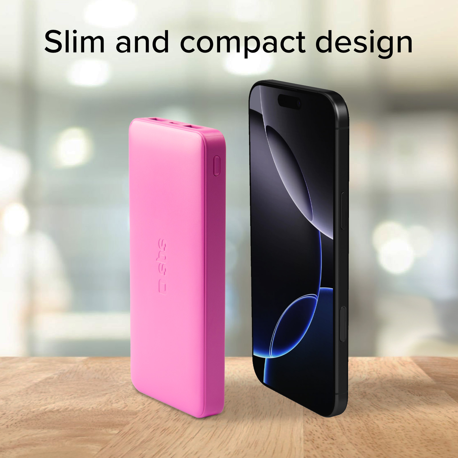 A pink power bank next to a black phone. Text on the power bank is visible.