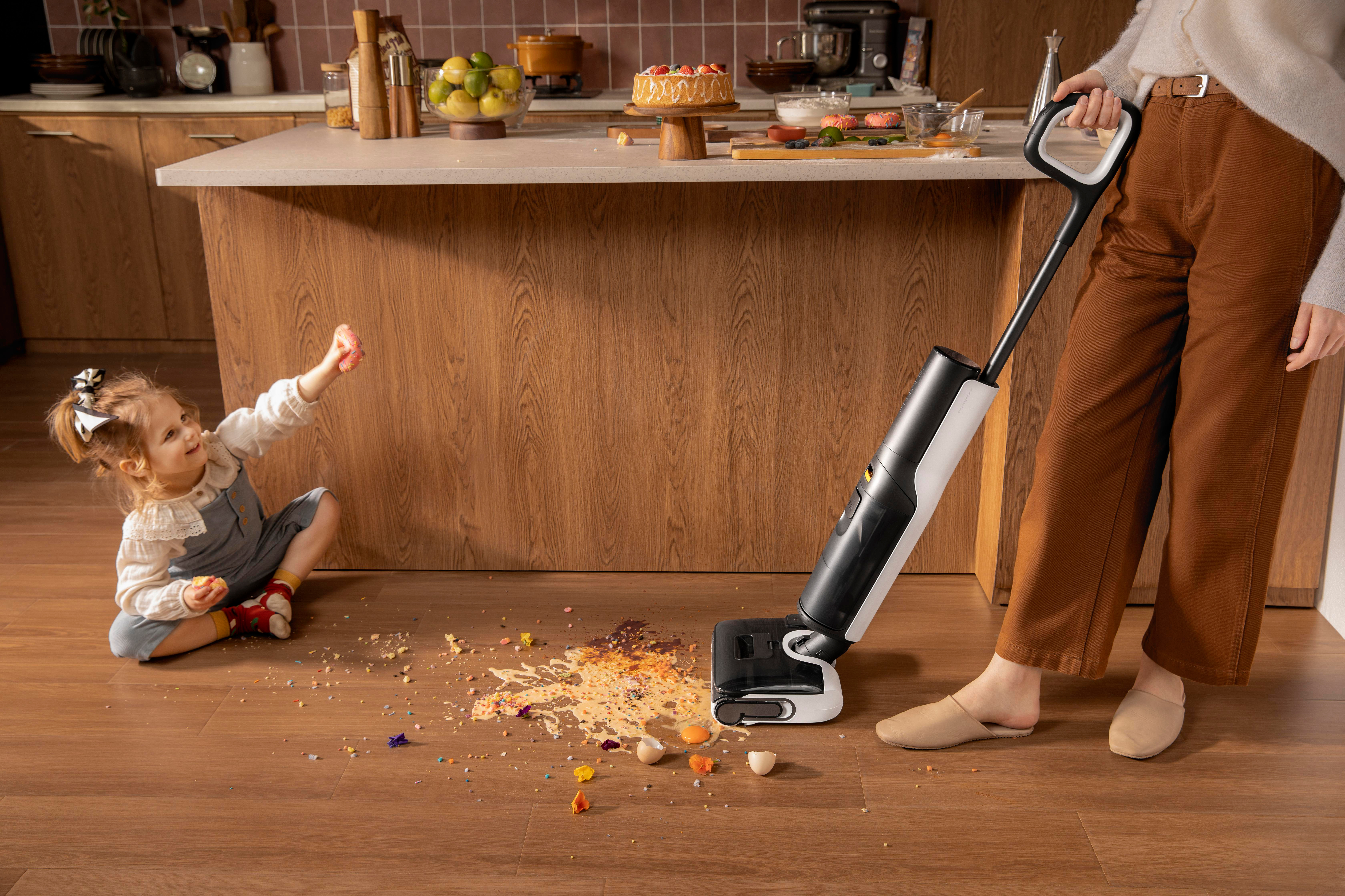 Ein Mädchen auf Holzboden sieht eine Reinigungsmaschine, die Essensreste reinigt.