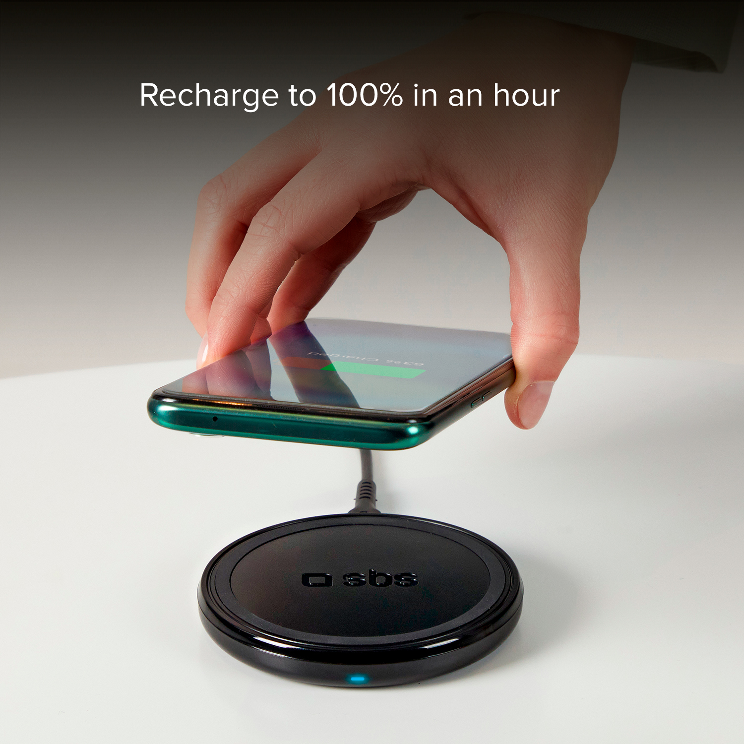 Hand die een telefoon boven een draadloze oplader houdt. Telefoon laadt op. Tekst: Opladen tot 100% in een uur.