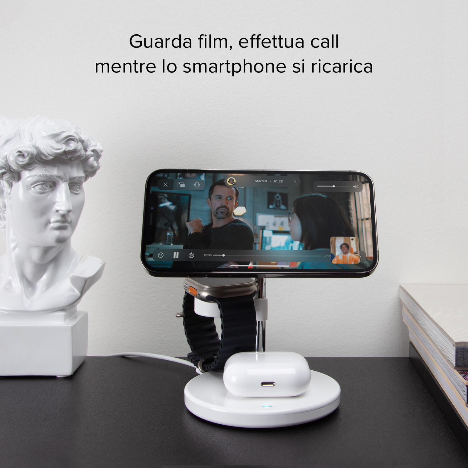Telefoon op een oplaadstandaard. Een man bekijkt een video, beeld ernaast.