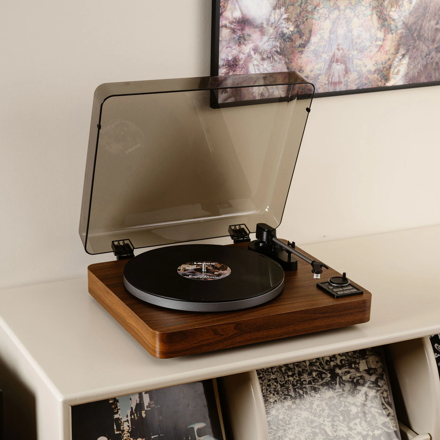 Un tourne-disque avec un disque noir, une finition en bois et un couvercle transparent.