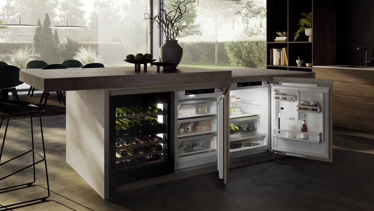 Moderne Kücheninsel mit eingebautem Kühl-/Gefrierschrank. Geöffnete Türen zeigen Lebensmittel. Weinregal links.