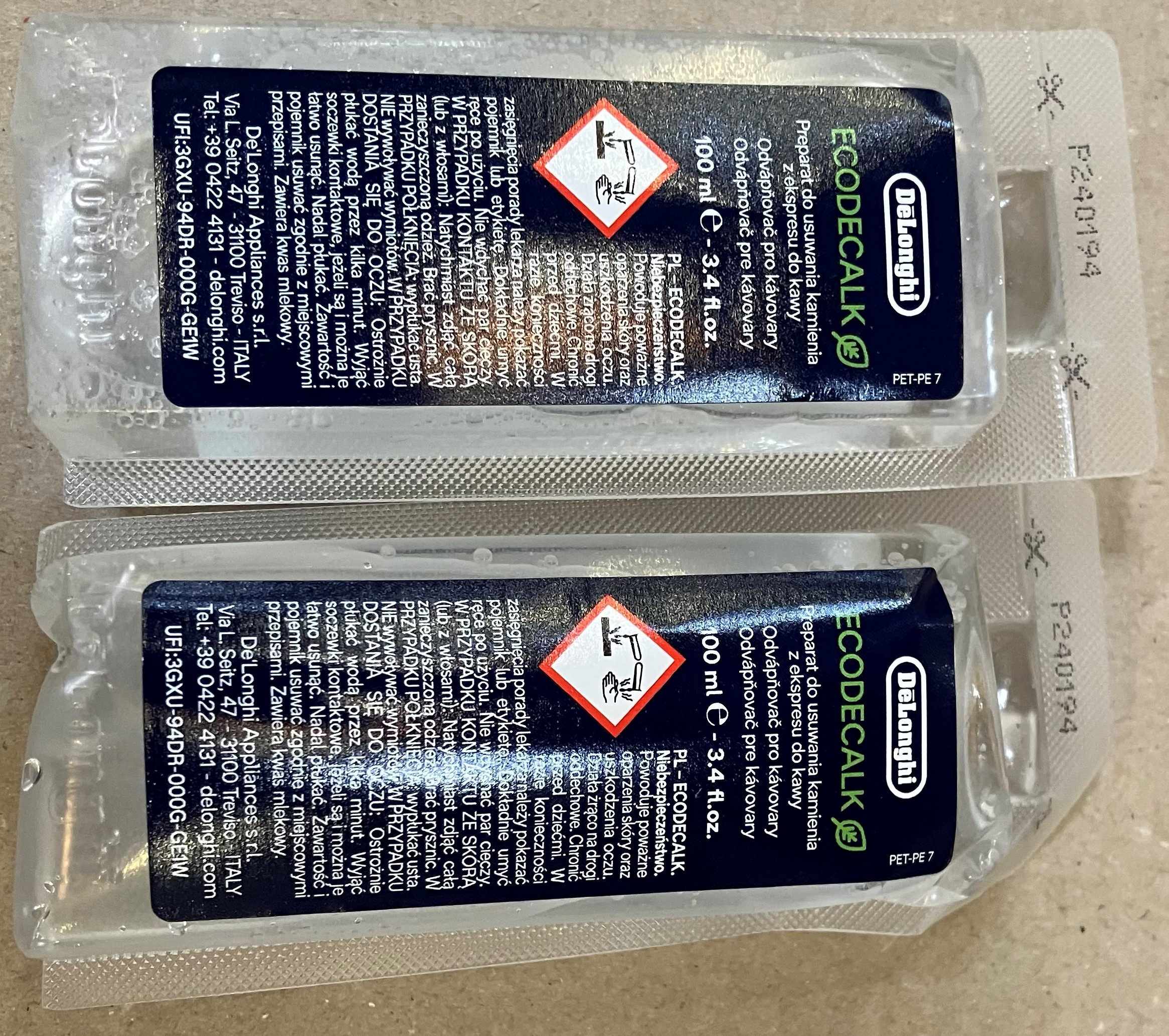 Dwie butelki DeLonghi Ecodecalk w przezroczystym plastikowym opakowaniu, z tekstem.