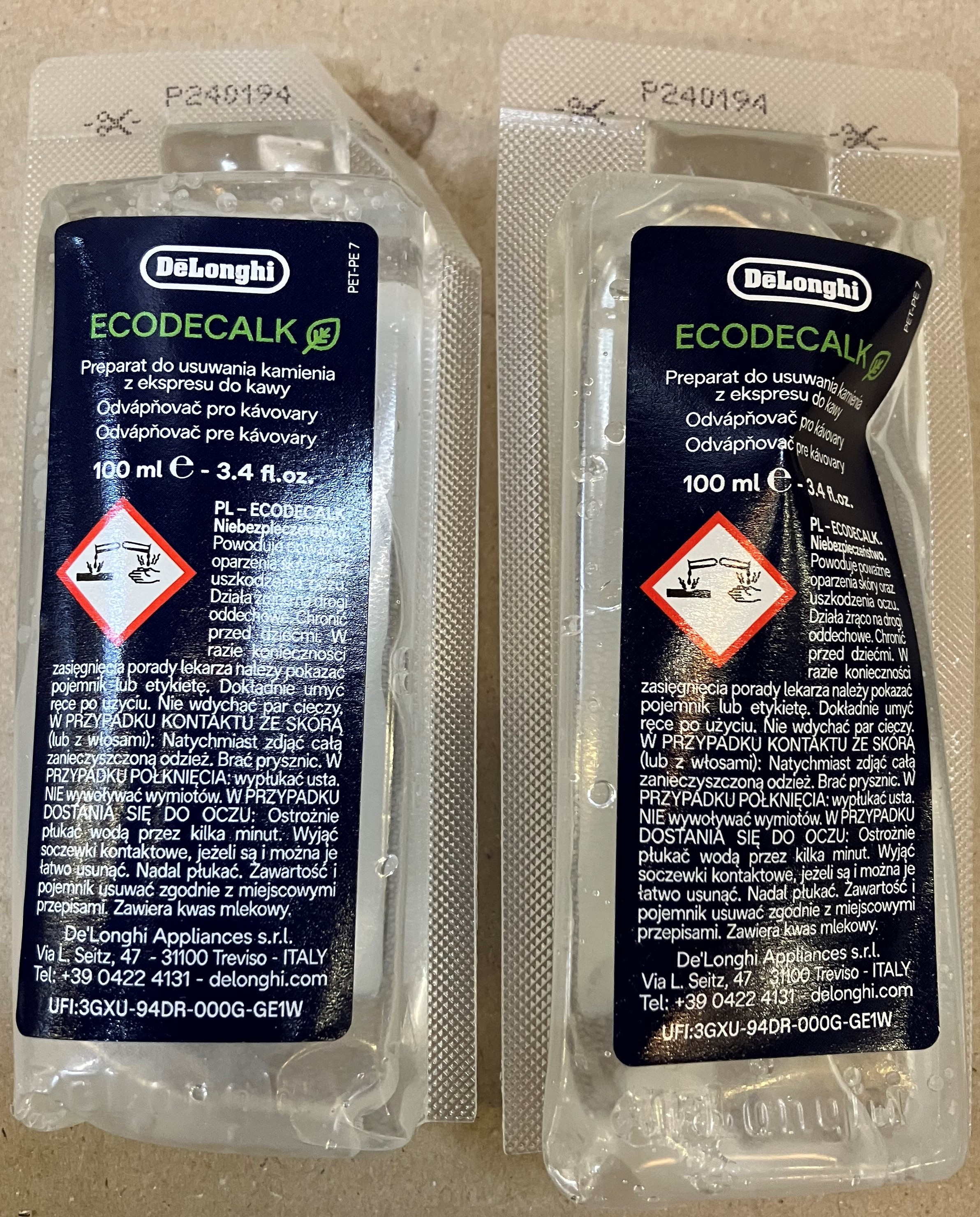 Dwie butelki DeLonghi Ecodecalk, każda z etykietą i symbolem ostrzegawczym. Butelki są przezroczyste.