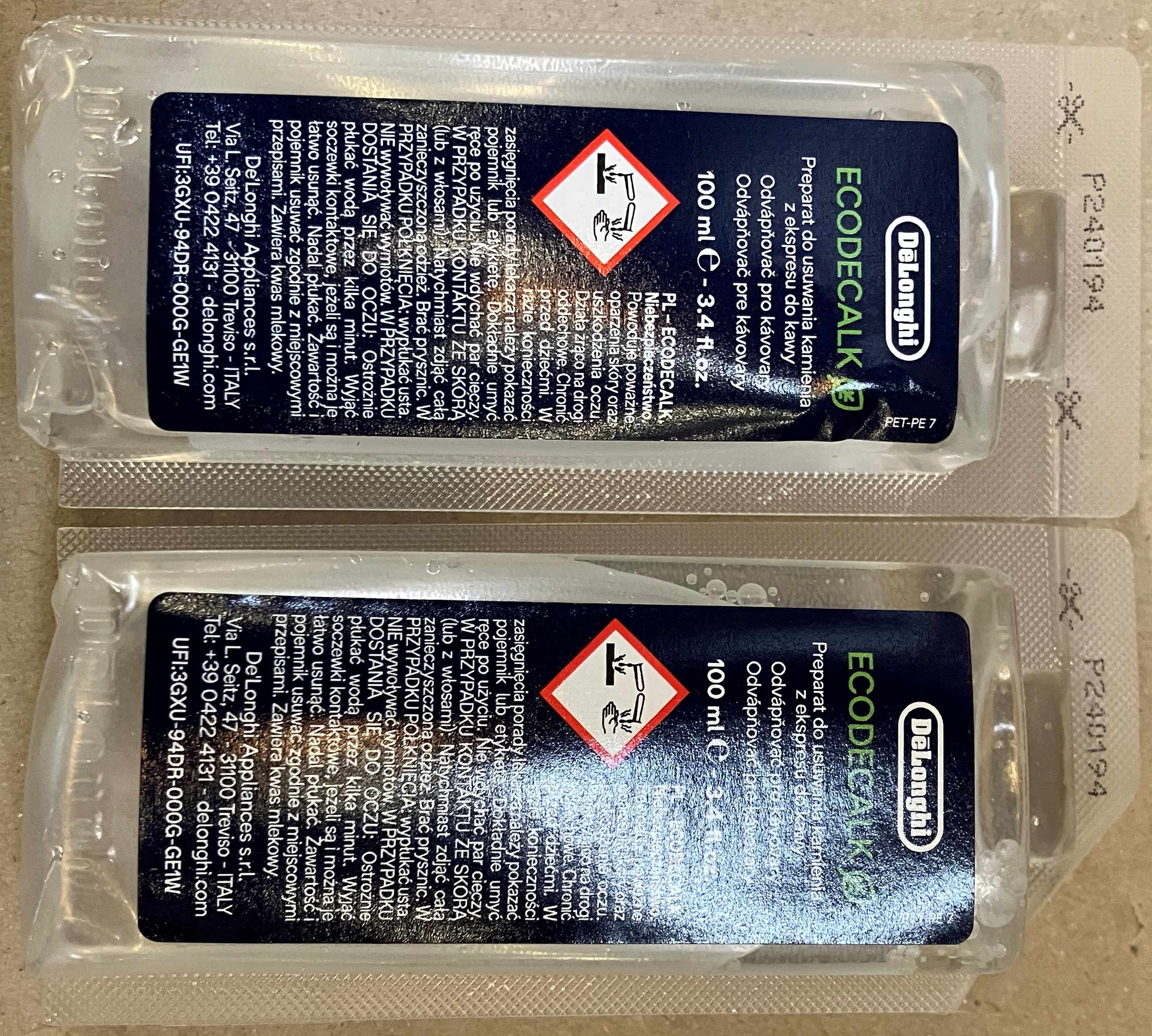 Dwa opakowania roztworu odkamieniającego do ekspresu do kawy, z tekstem.