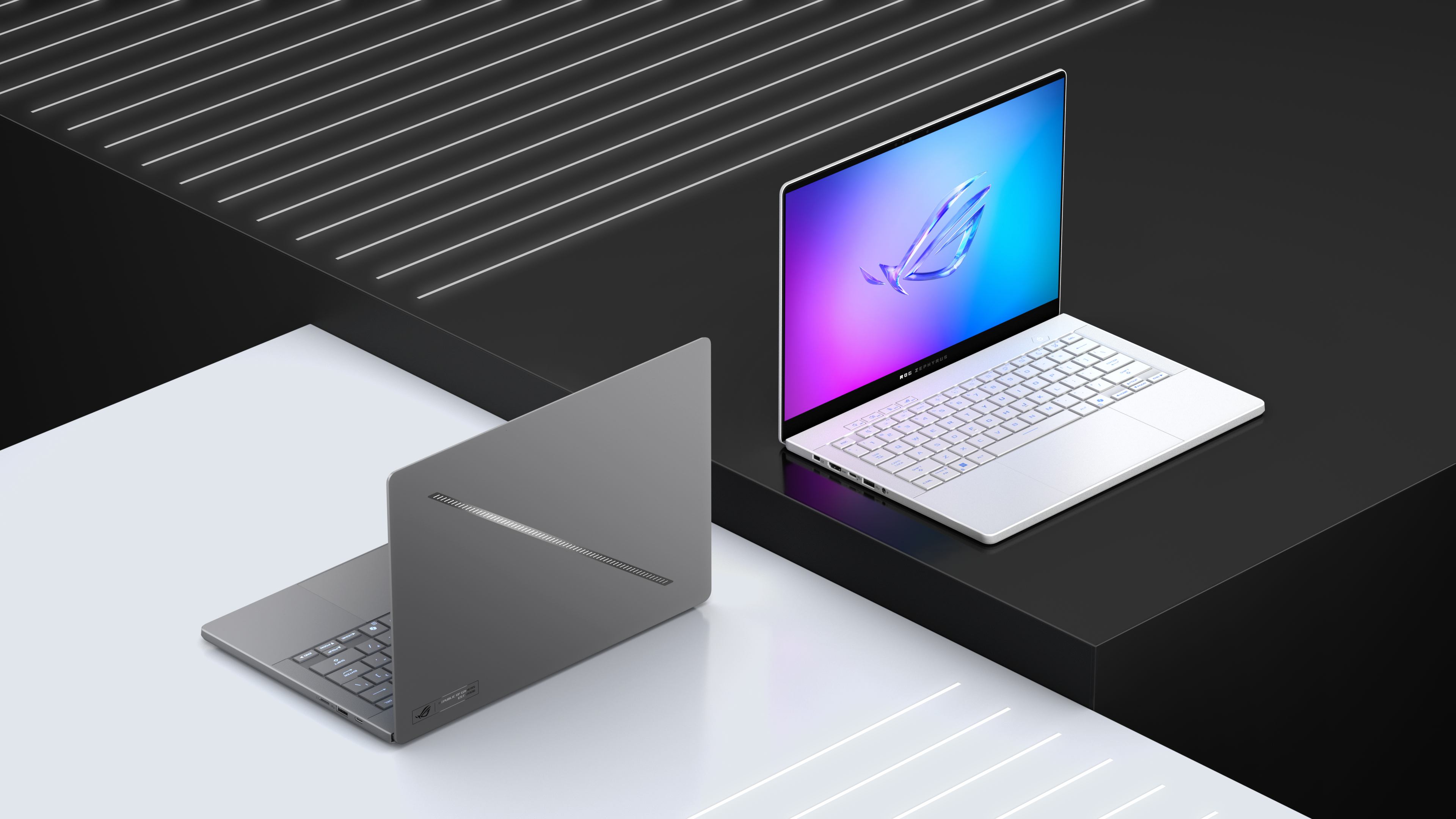 Zwei Laptops auf schwarzer und weißer Oberfläche. Einer geschlossen, einer offen, leuchtender Bildschirm.