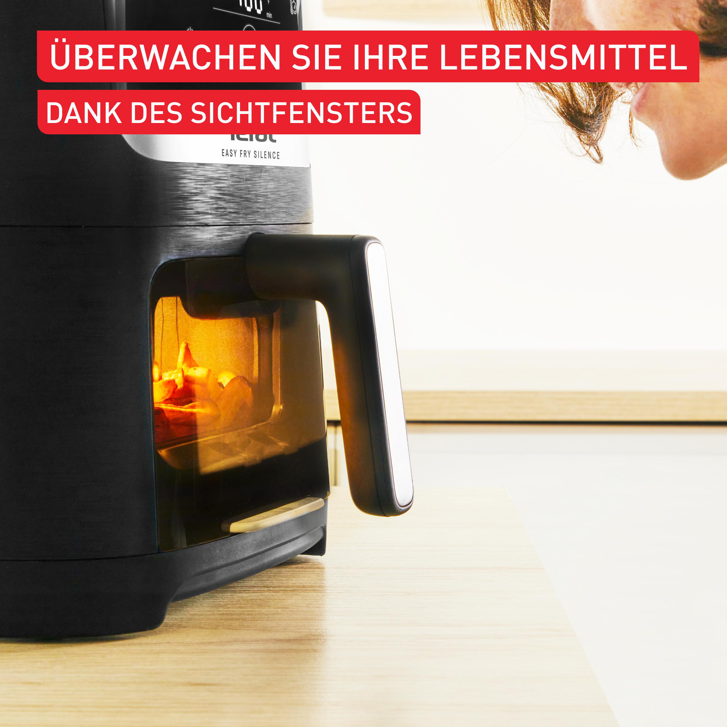 Heißluftfritteuse mit Essen durch ein Fenster, roter Text.