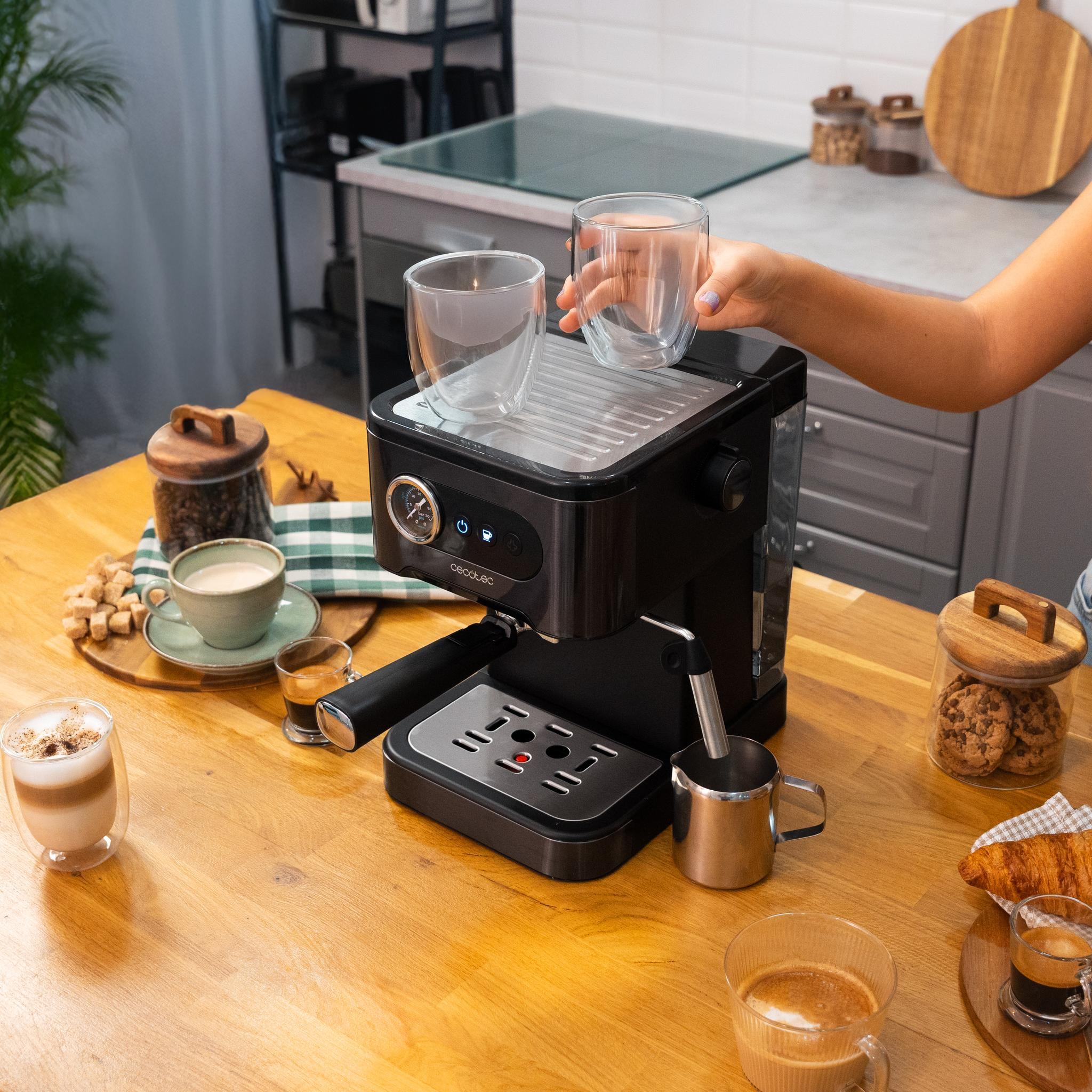 Persona preparando café con una máquina de espresso. Varios artículos relacionados con el café en la mesa.