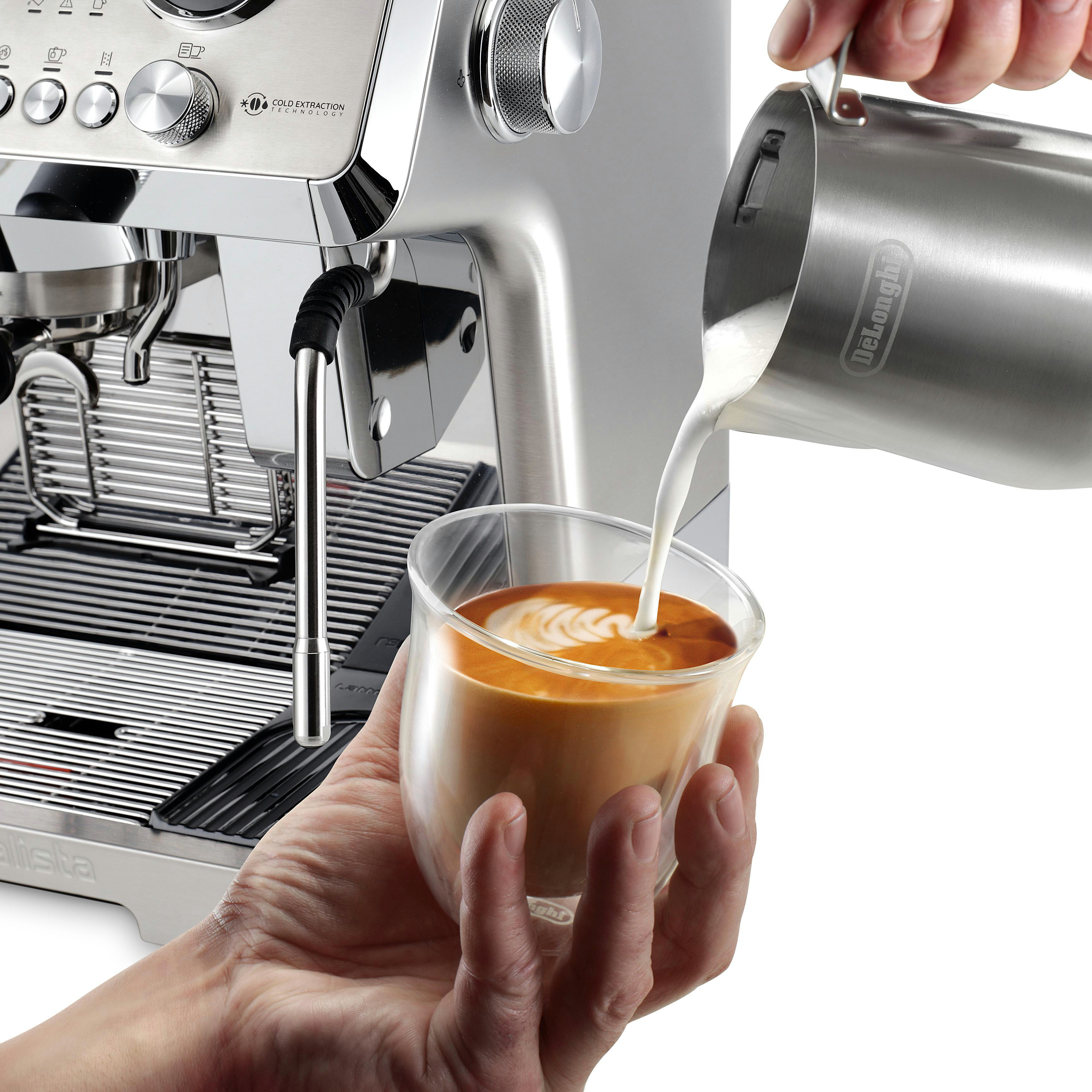 Person gießt Milch in ein Glas Kaffee.