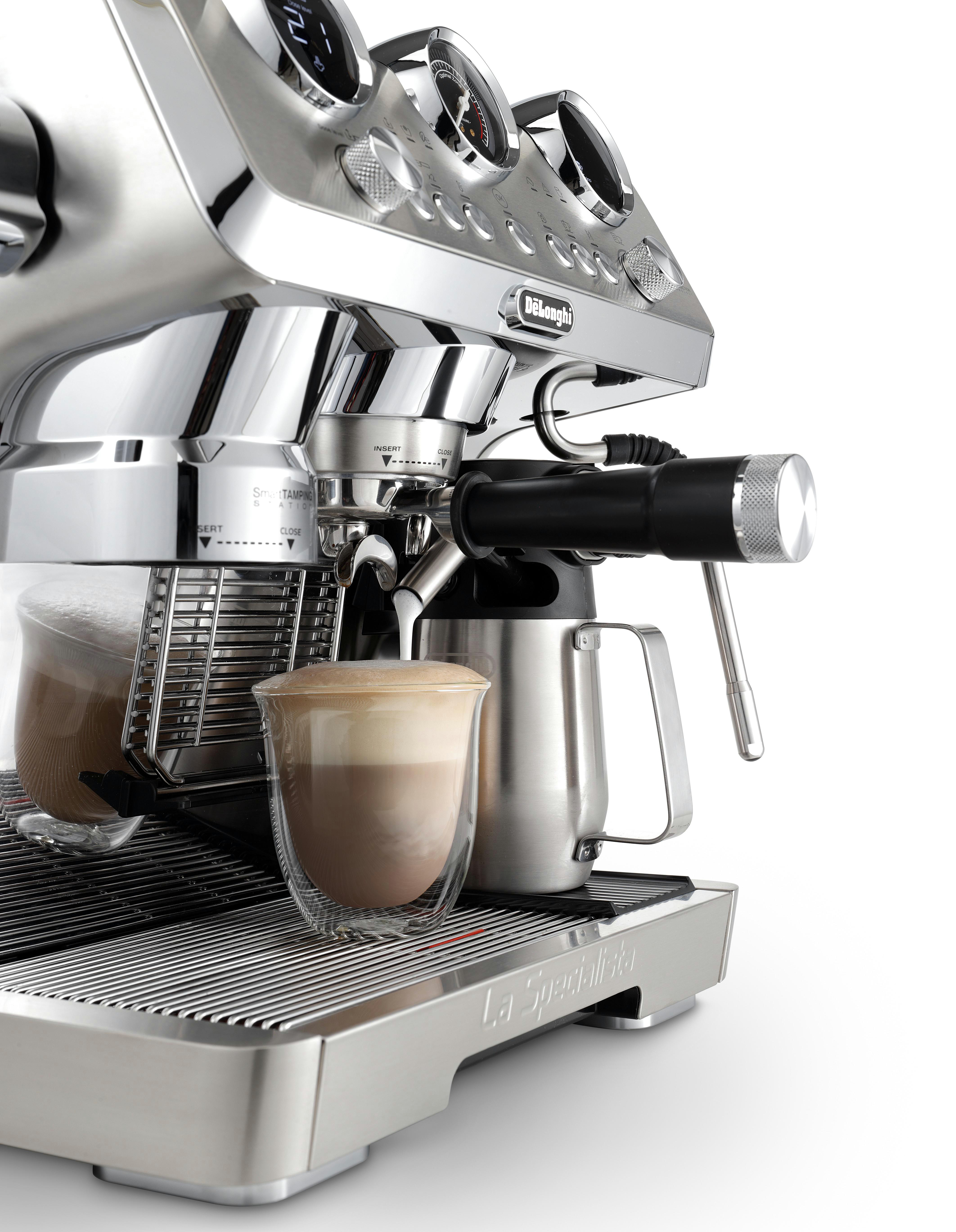 Silberne Espressomaschine mit Kaffee. Eine Tasse und ein Milchschaumkännchen sind vorhanden.