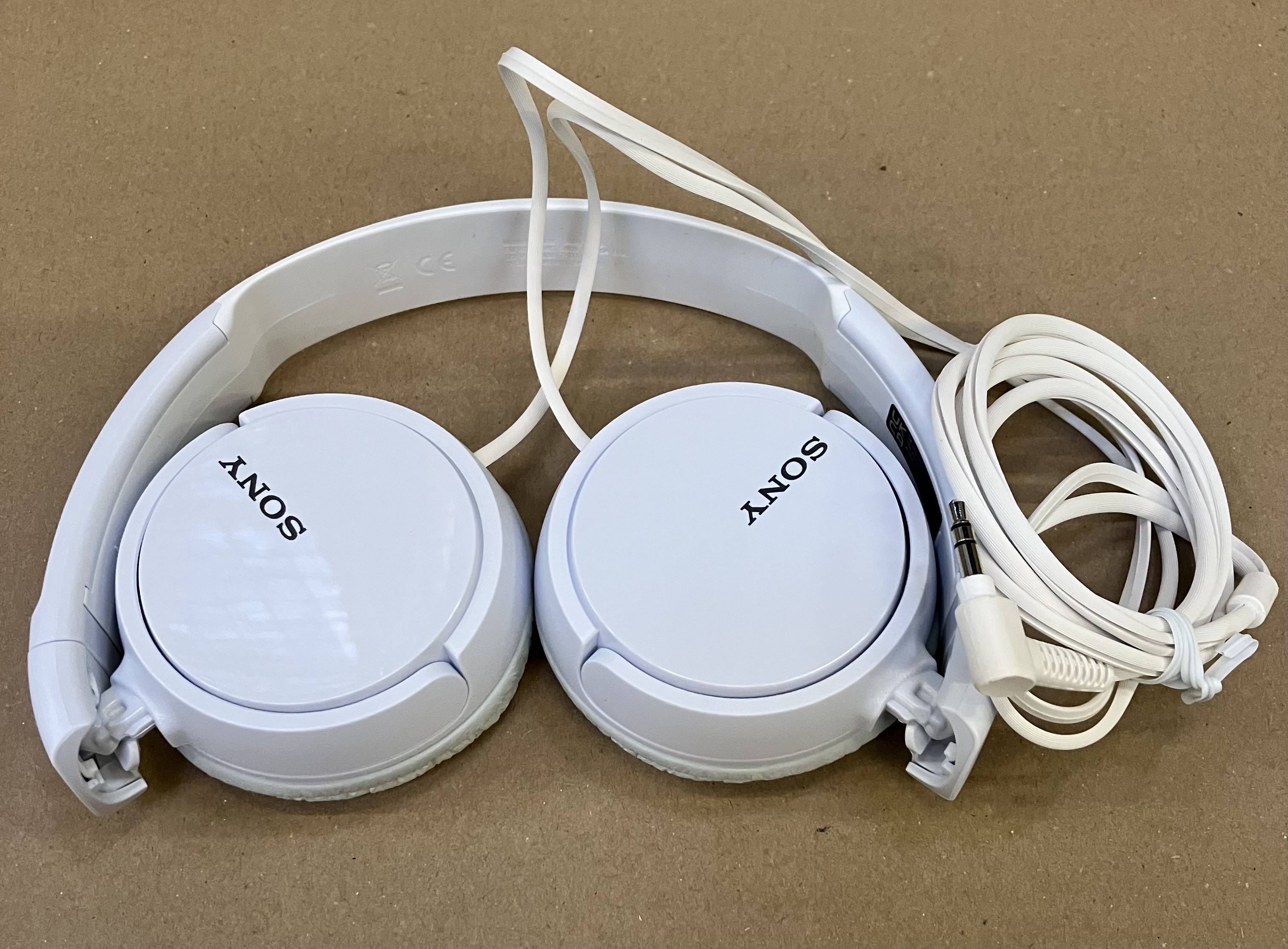 Białe słuchawki z logo SONY i białym kablem.