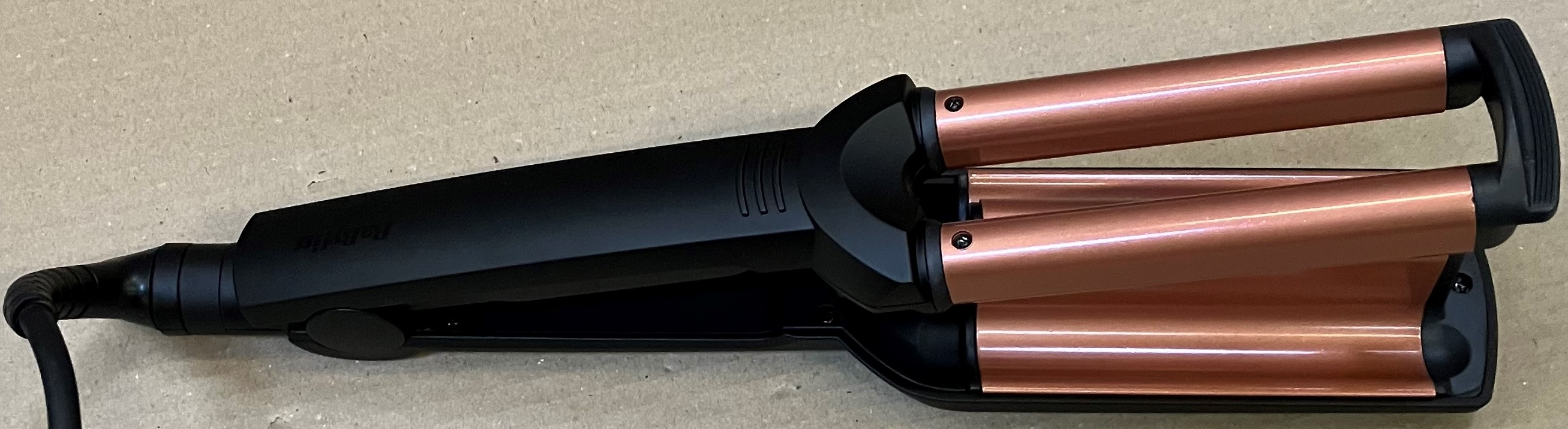 Prostownica do włosów: czarna z lufami w kolorze różowego złota, z przewodem i zamknięta. Widok z góry.