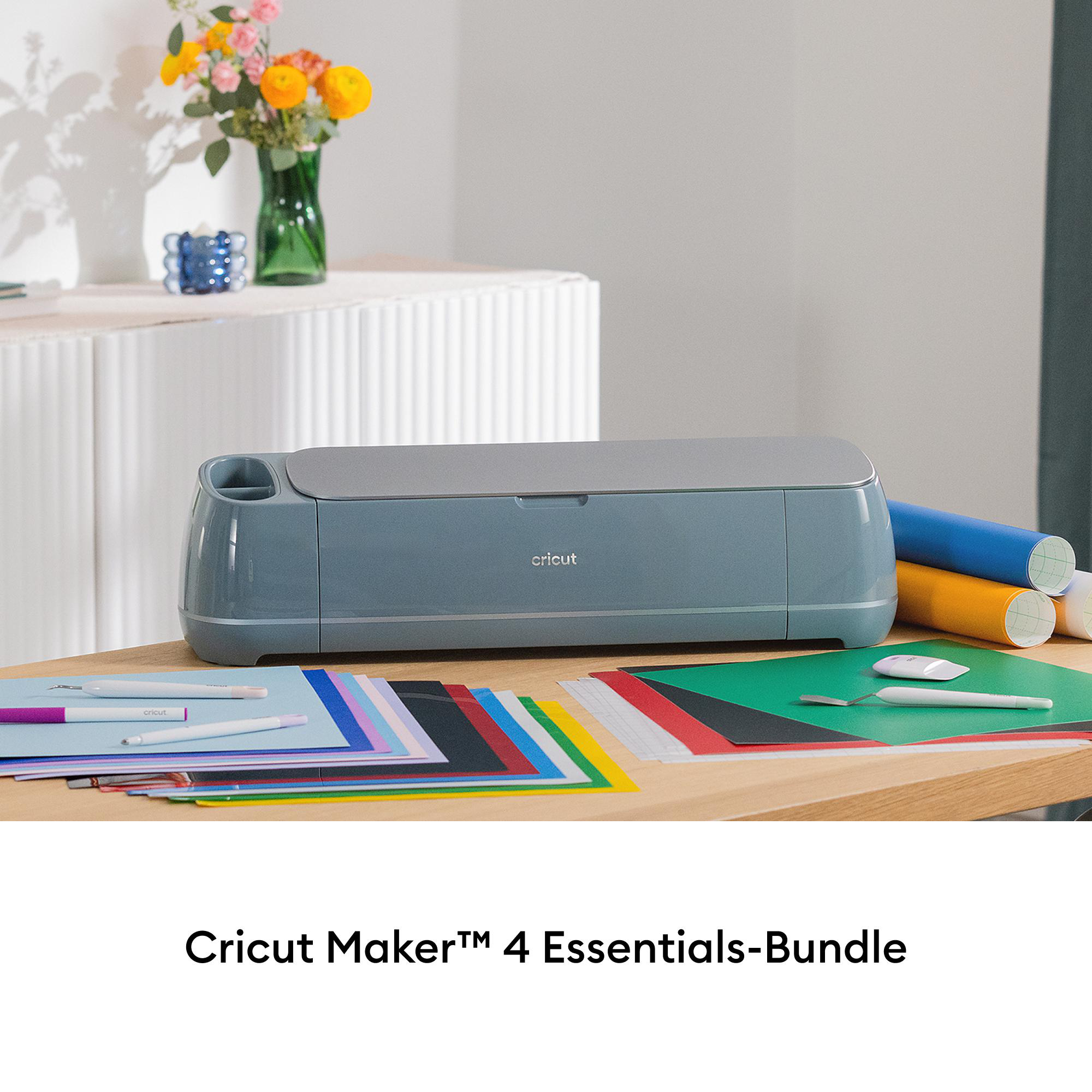 Cricut Maker 4 Essentials Bundle mit Materialien auf einem Holztisch mit weißem Hintergrund.