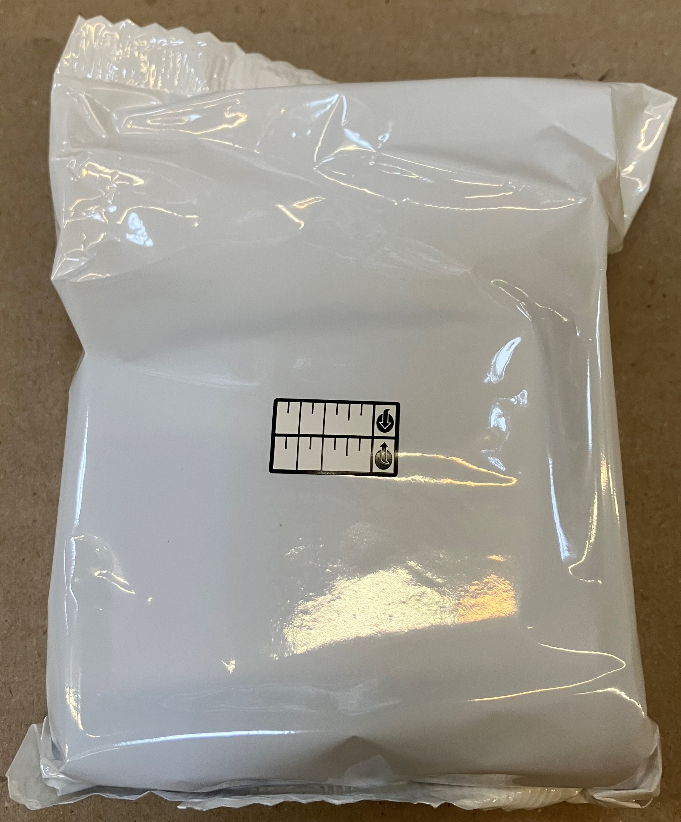 Biała plastikowa torba z etykietą. Etykieta ma poziome linie i tekst.