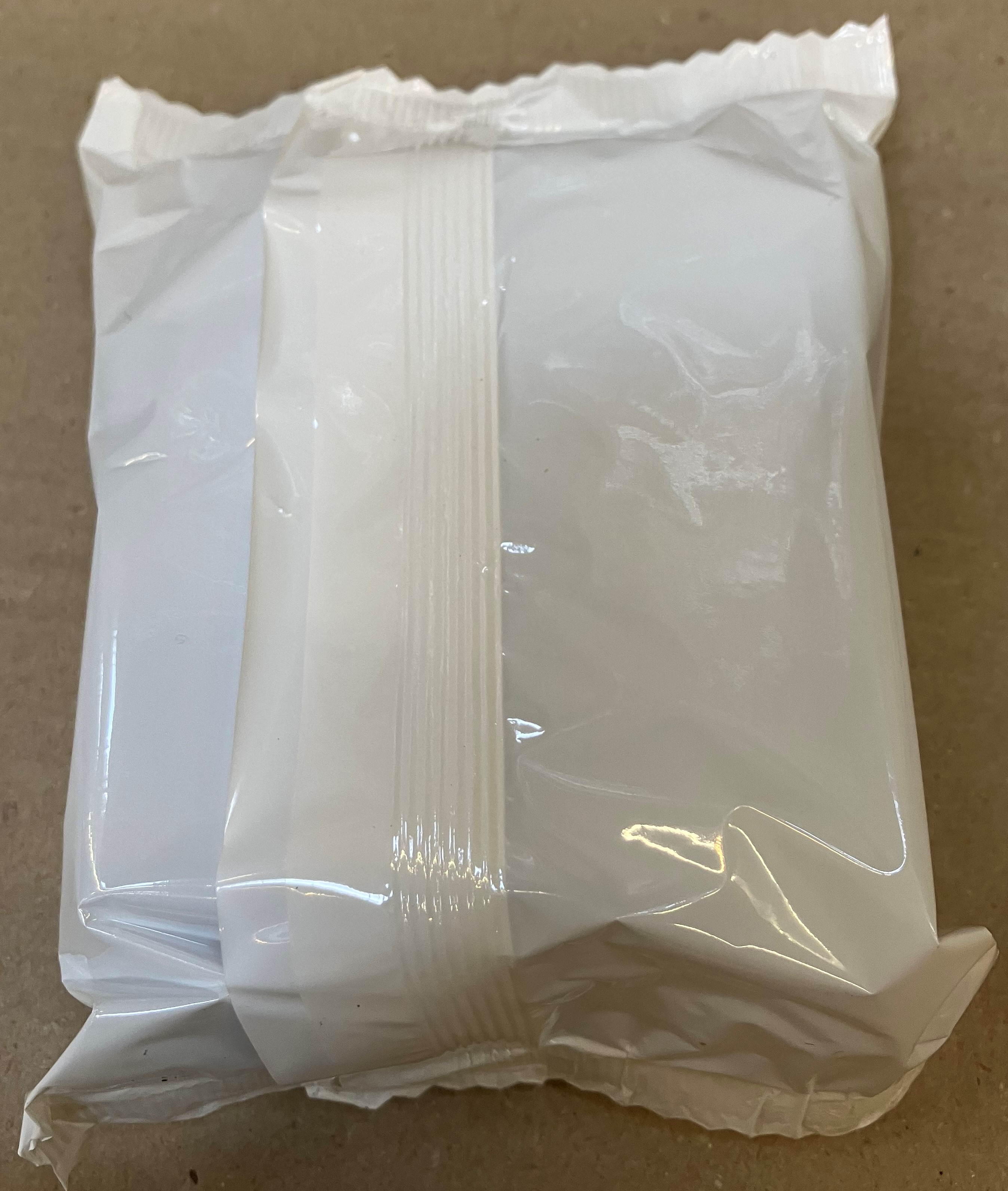 Białe plastikowe opakowanie, zamknięte i złożone, zawierające nieznany produkt.