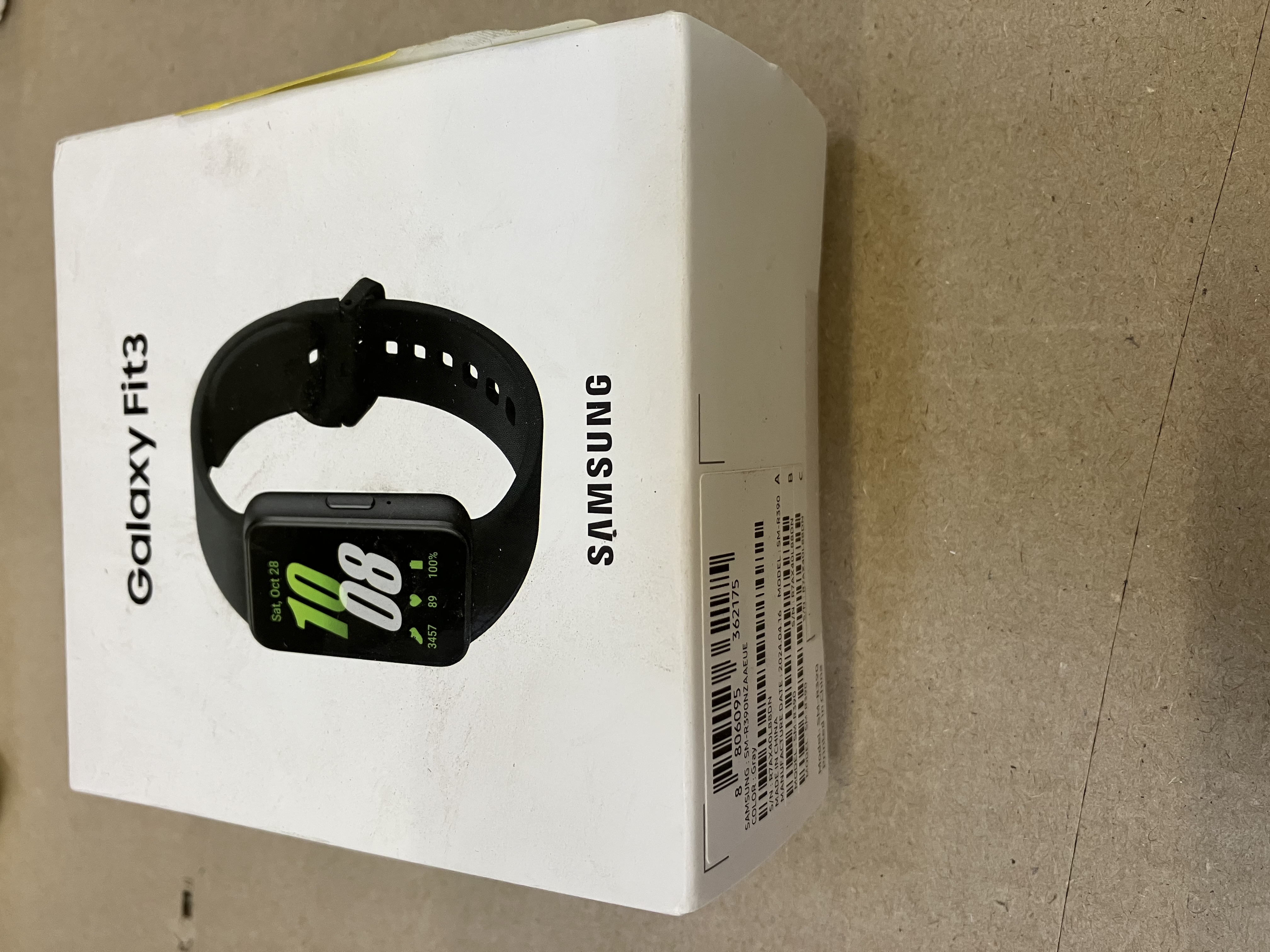 Białe pudełko Samsung Galaxy Fit3. Pokazuje zegarek z czarnym paskiem.