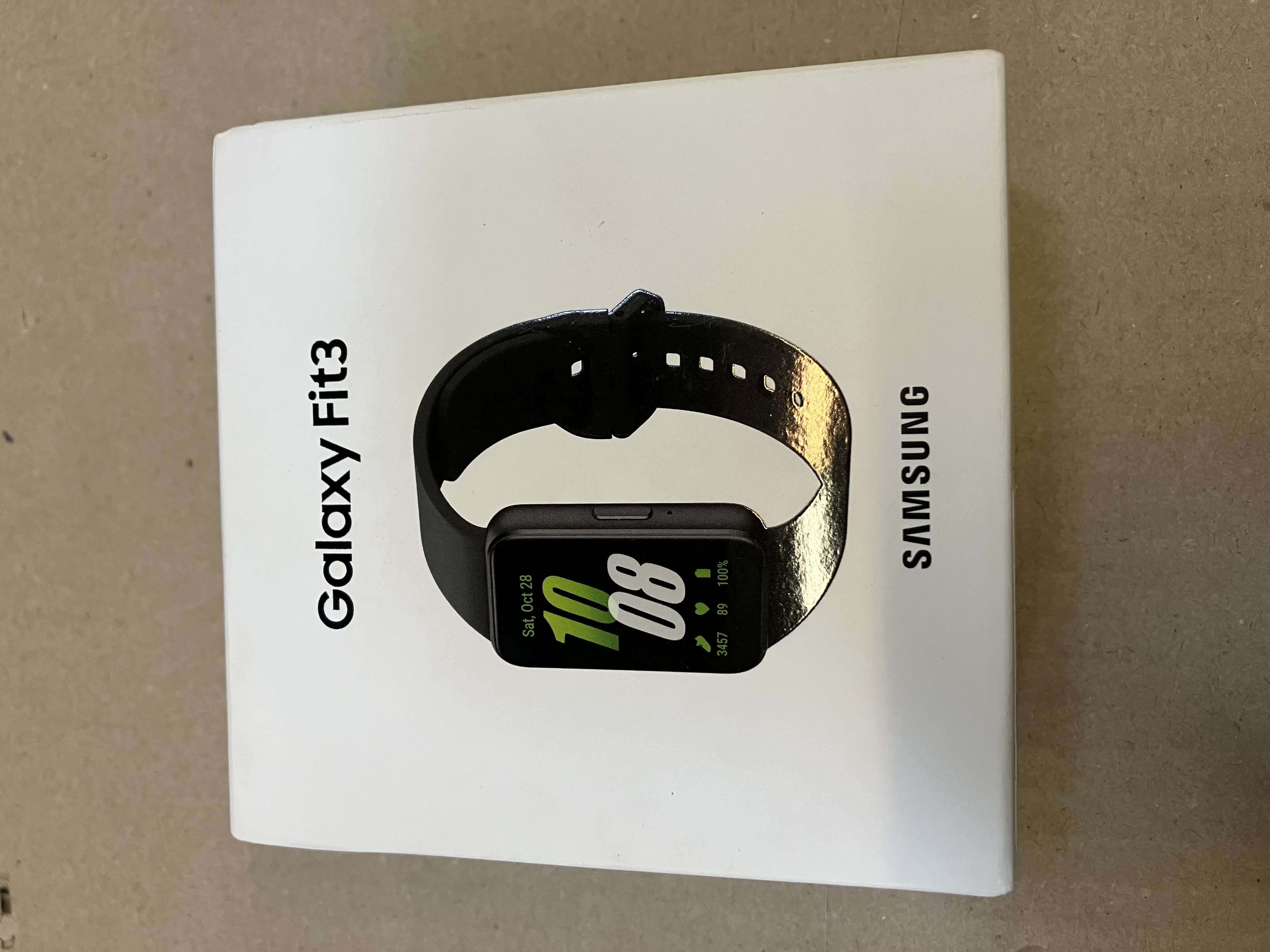 Białe pudełko smartwatcha Samsung Galaxy Fit3, z widocznym zegarkiem.