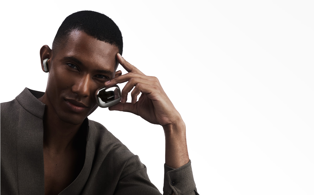 Mężczyzna trzymający etui na słuchawki, uśmiechający się na białym tle.