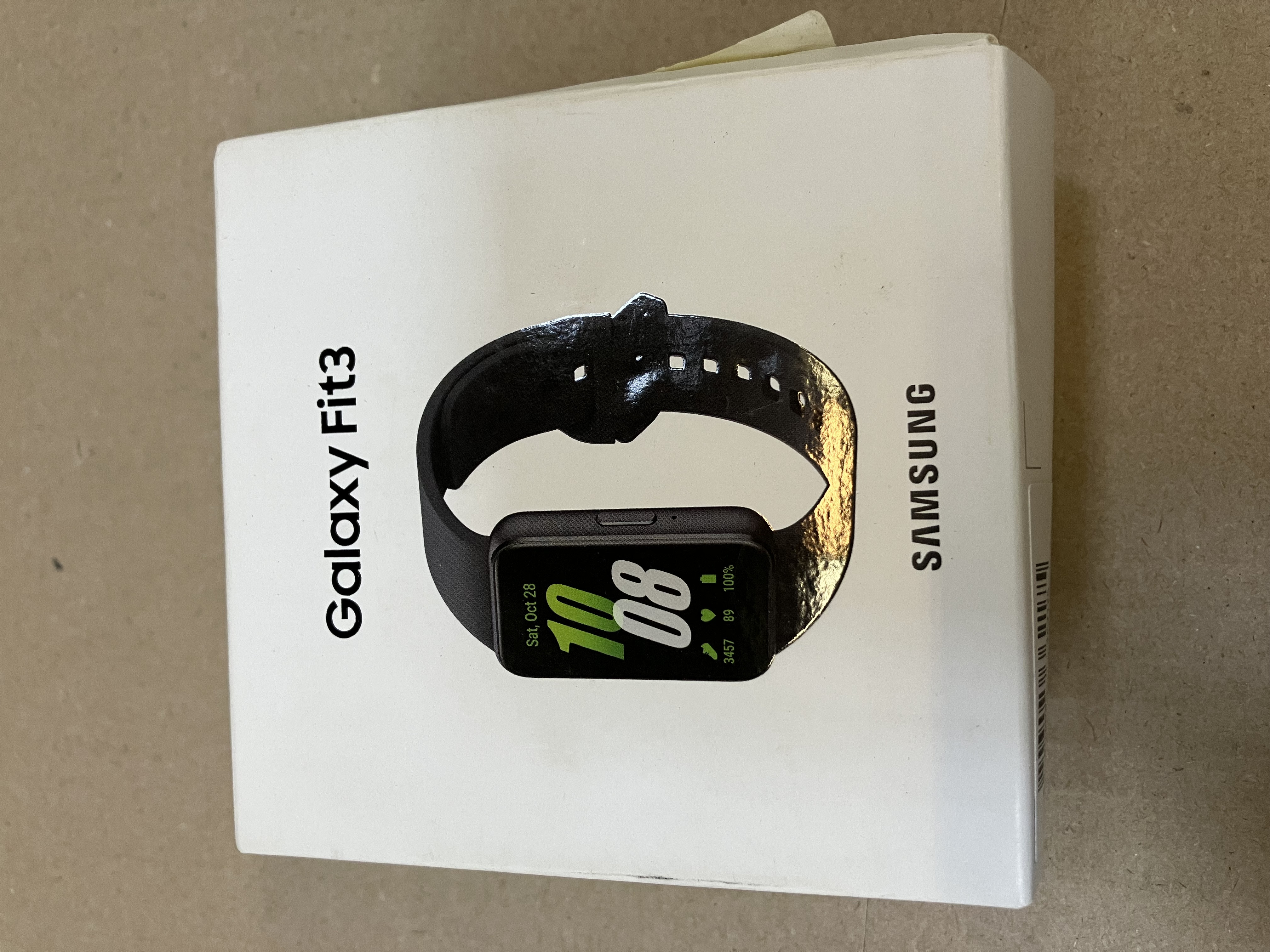 Białe pudełko smartwatcha Galaxy Fit3, pokazujące zegarek i nazwę marki.
